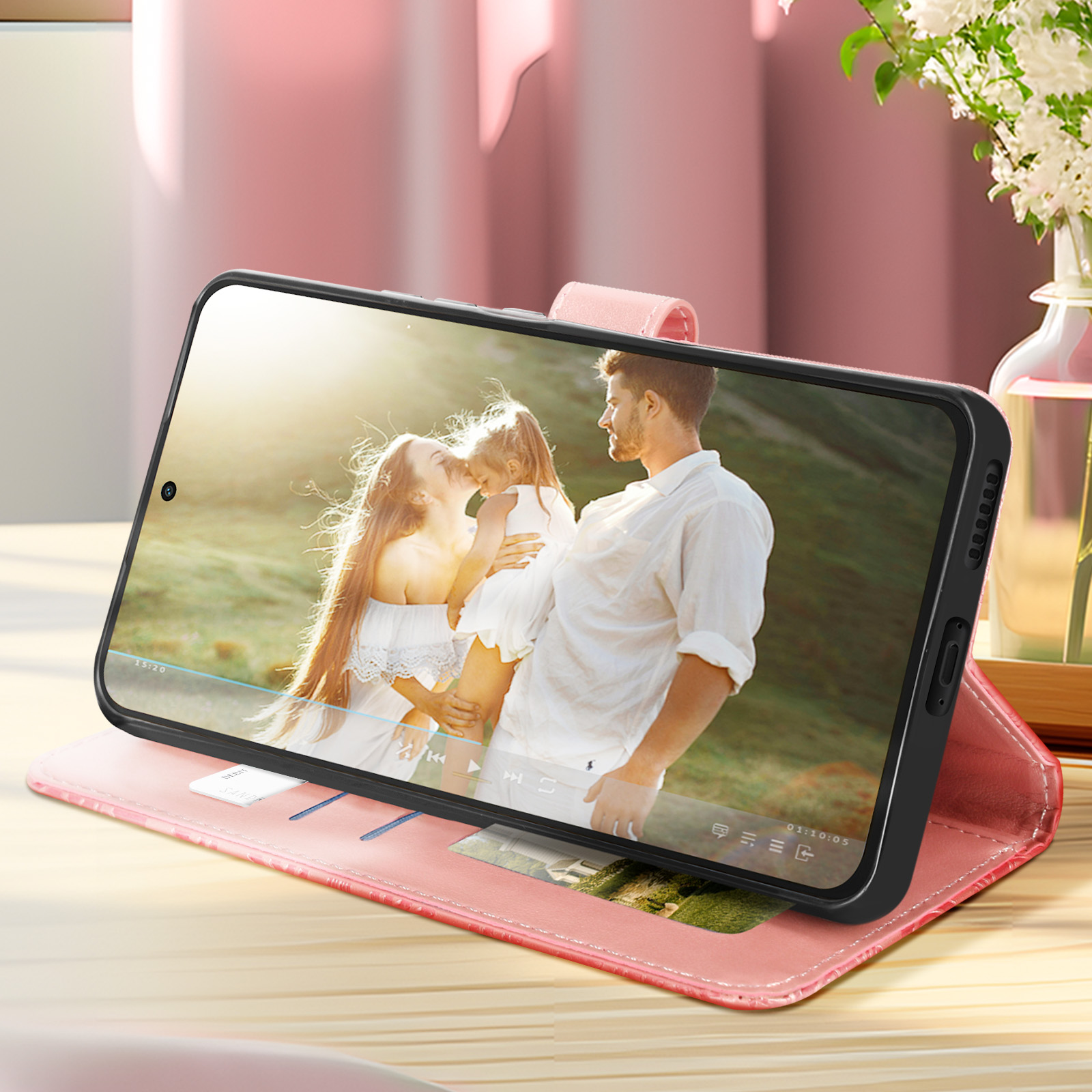 Custodia per telefono rosa, aperta. Una coppia e un bambino guardano un video.