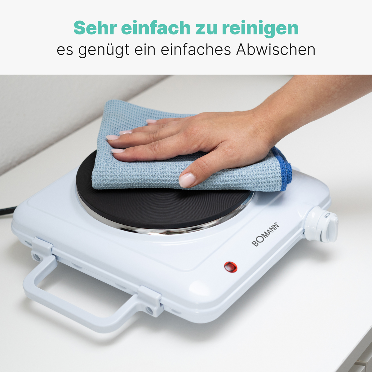 Ręka wyciera niebieską szmatką białą elektryczną płytę grzejną. Tekst mówi, że jest łatwa do czyszczenia.