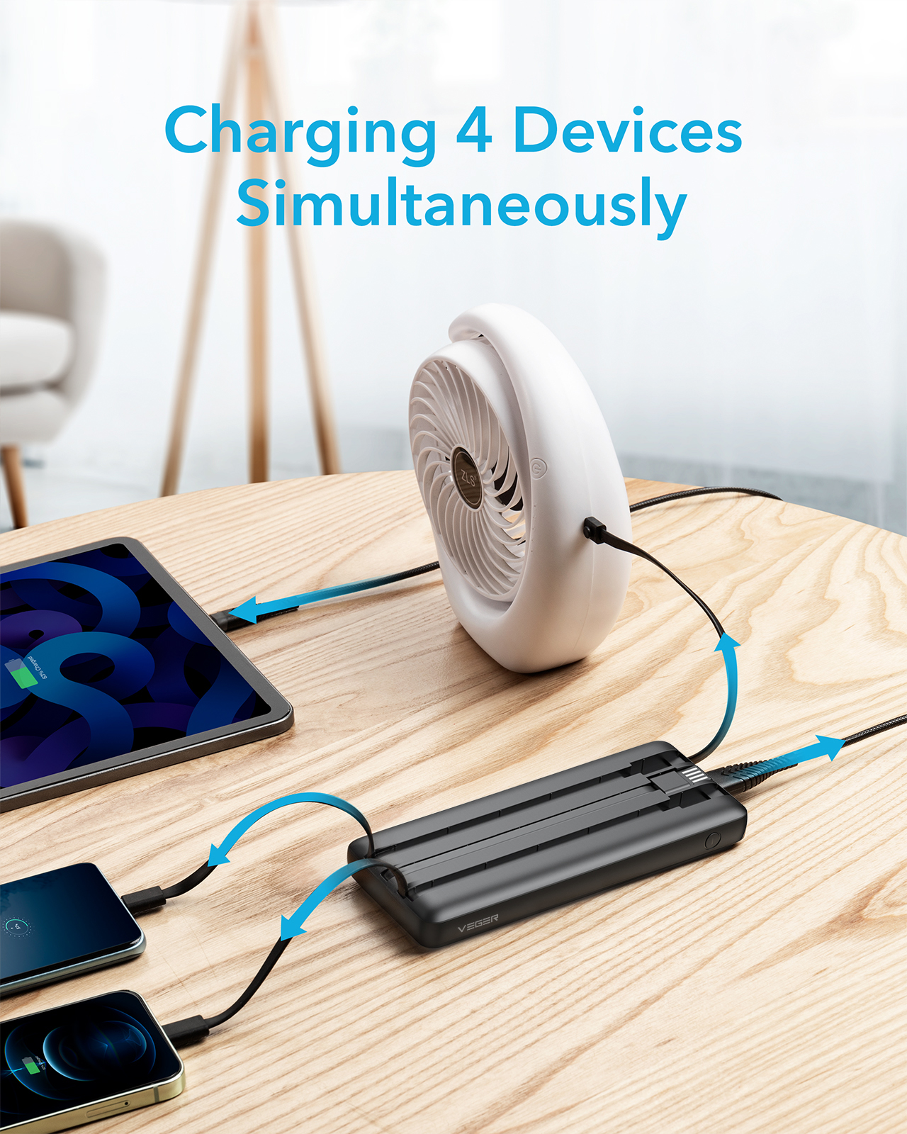 Geräte laden. Ein Tablet, zwei Telefone und ein Ventilator sind an eine schwarze Powerbank angeschlossen.