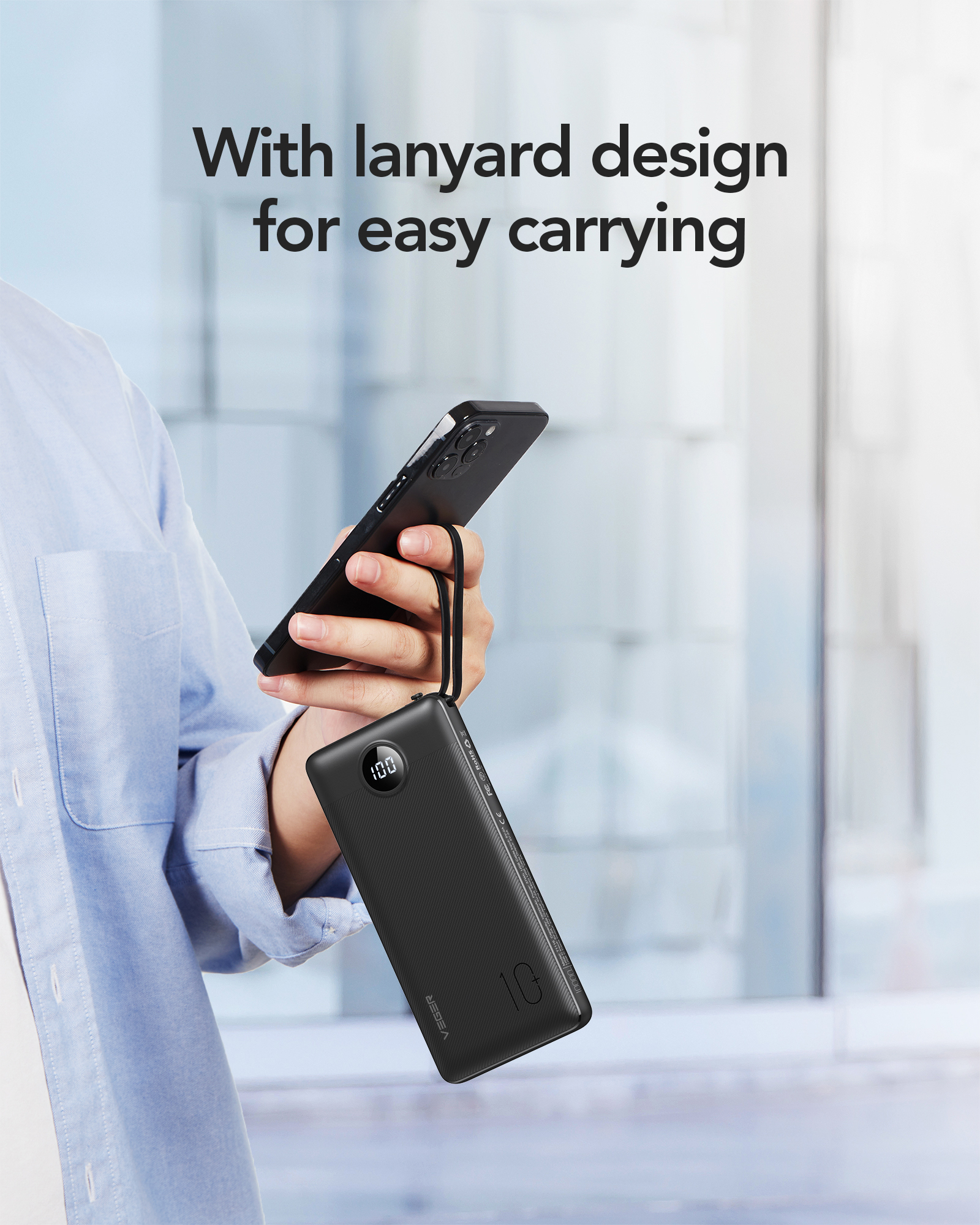 Eine Person hält eine schwarze Powerbank mit einem schwarzen Telefon. Text: Mit Lanyard-Design für einfaches Tragen.