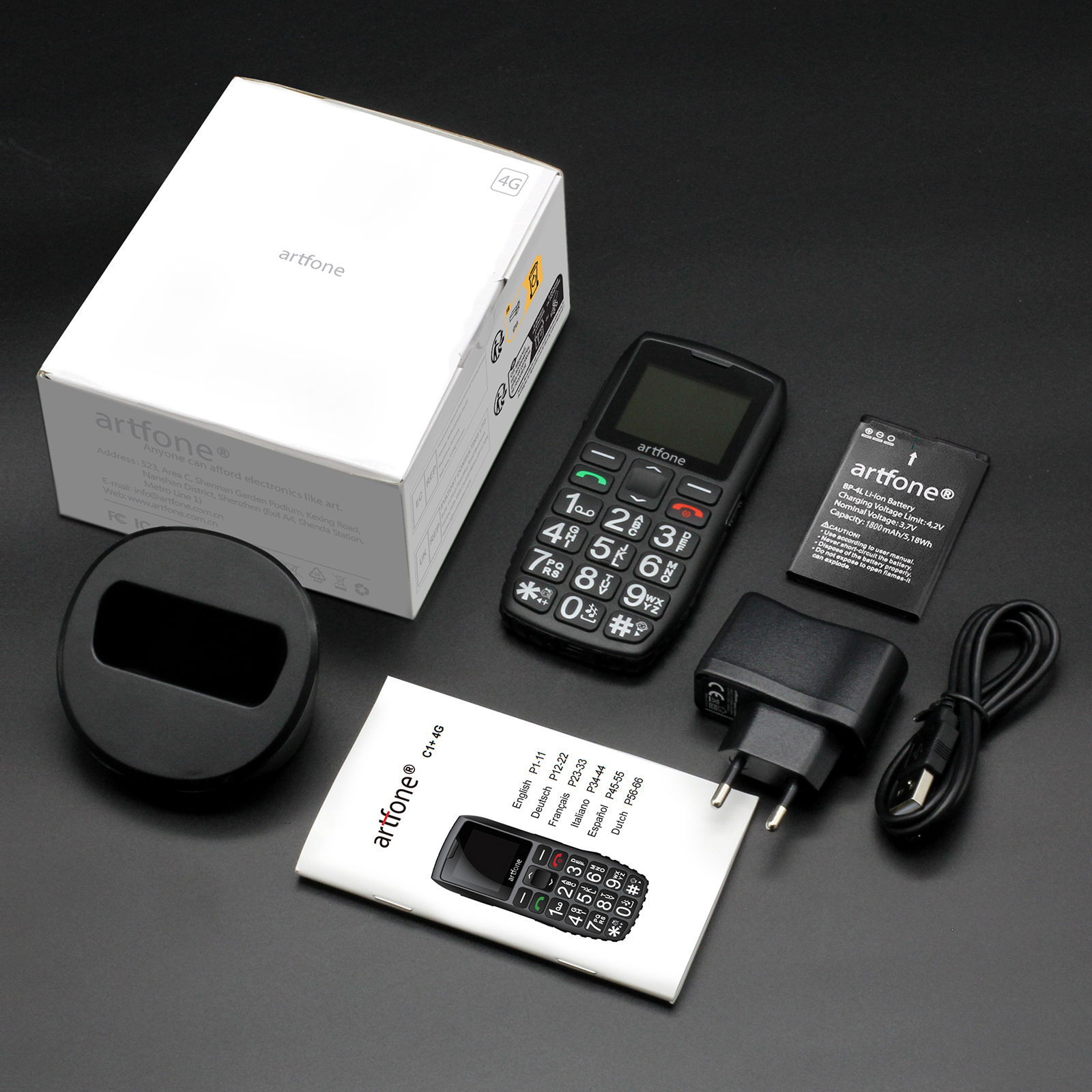 Schwarzes Artfone-Telefon mit Zubehör: Ladegerät, Akku und Handbuch auf schwarzer Oberfläche.