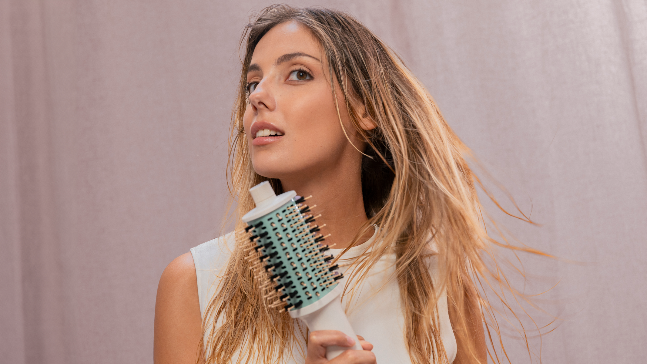 Donna con spazzola per capelli, guarda in alto, rivolta verso lo spettatore.