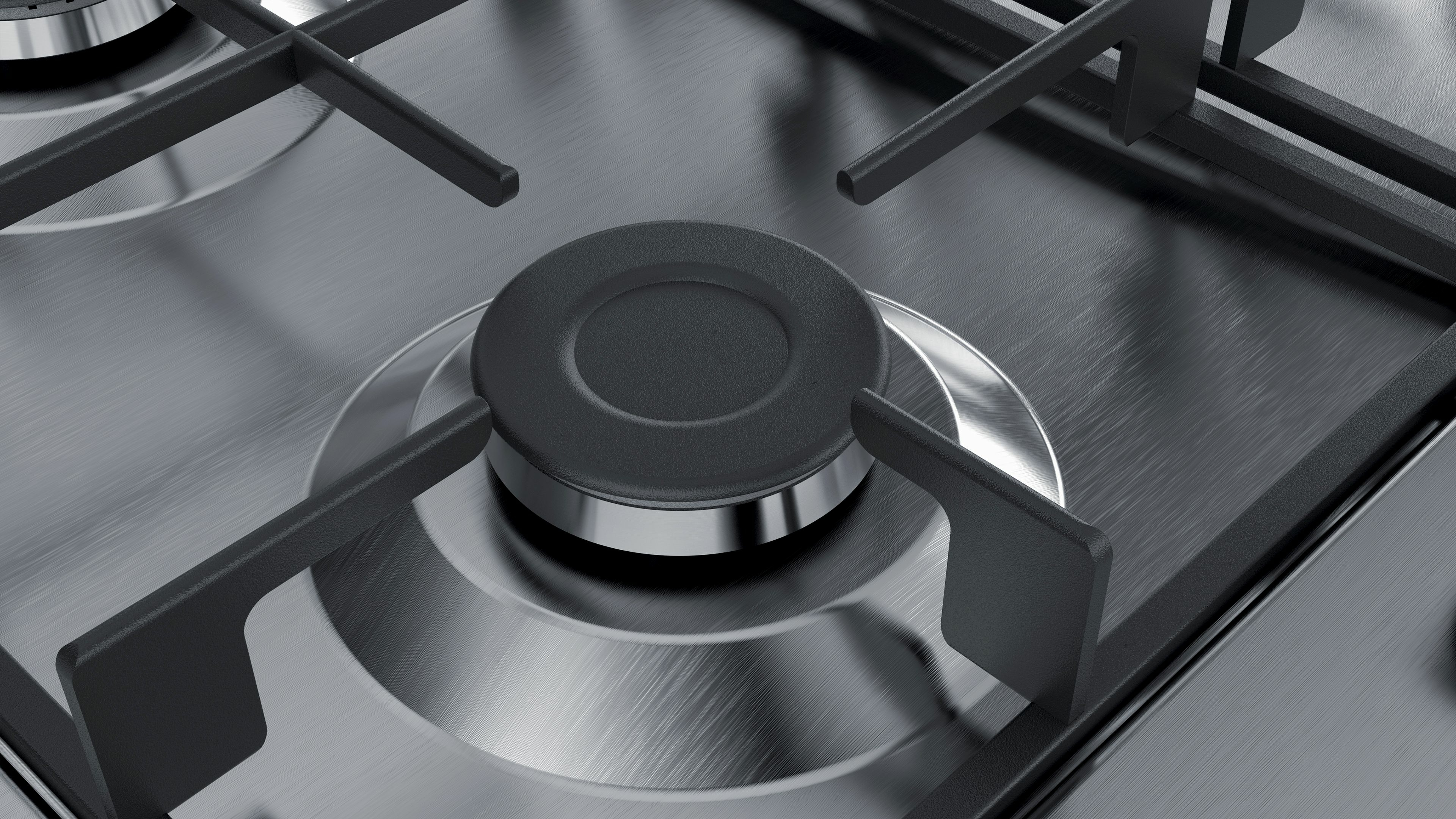 Zbliżenie na kuchenkę gazową ze stali nierdzewnej z czarnymi rusztami palników. Palniki są ciemne.