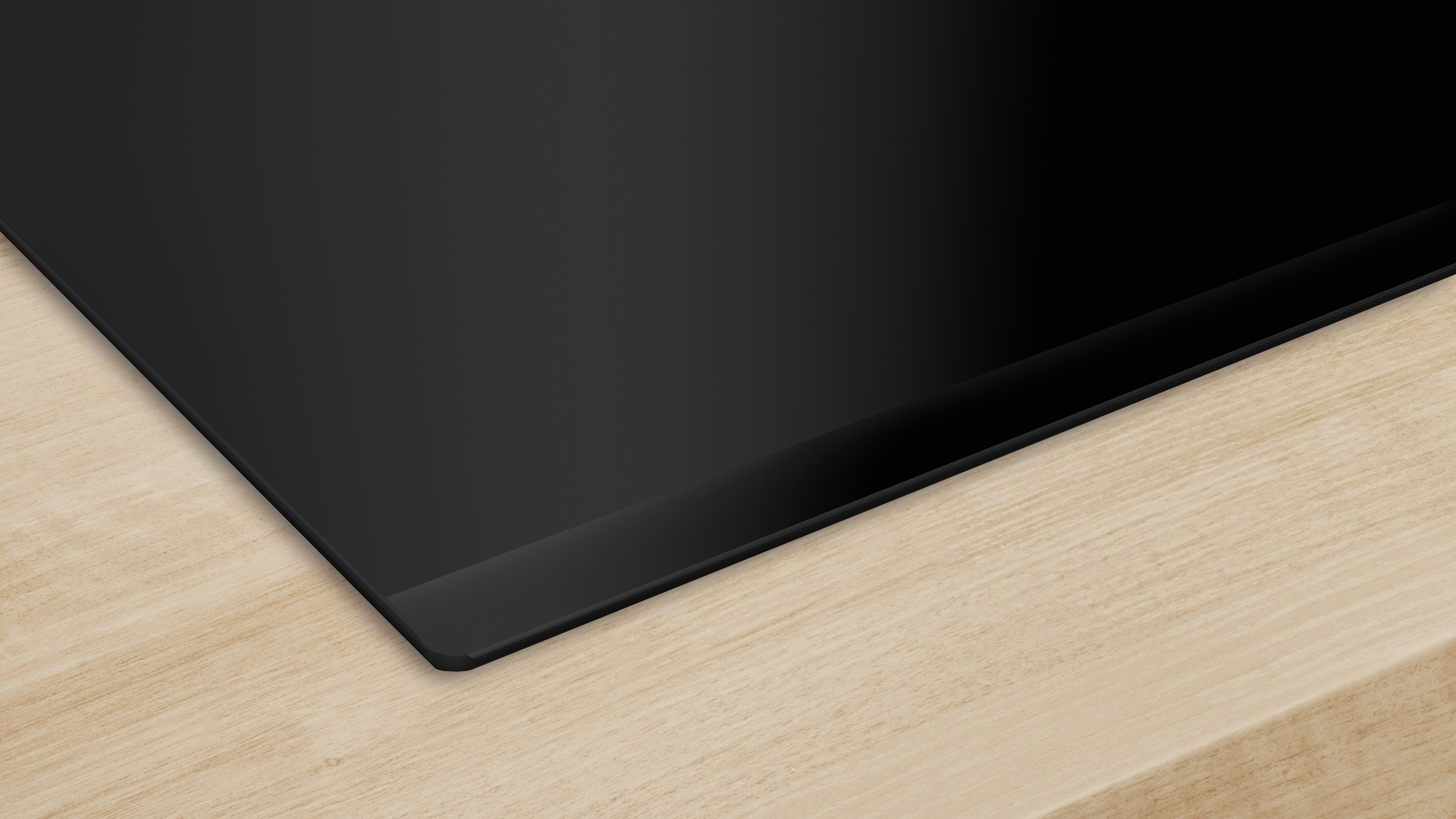 Czarna płyta grzewcza na drewnianej powierzchni. Pokazuje róg płyty grzewczej.