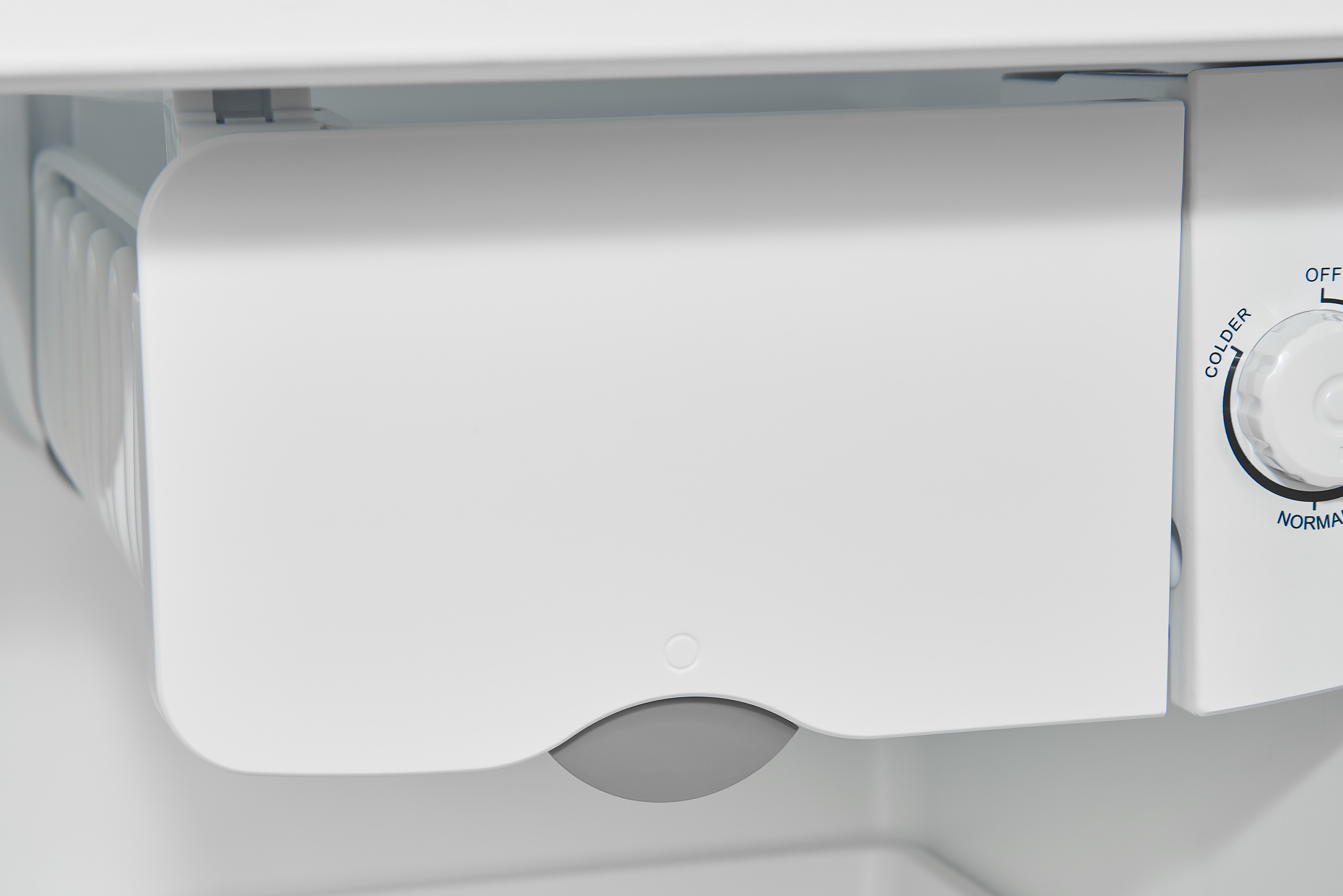 Compartimento de la máquina de hielo del refrigerador blanco. Un contenedor de plástico blanco con dispensador gris.