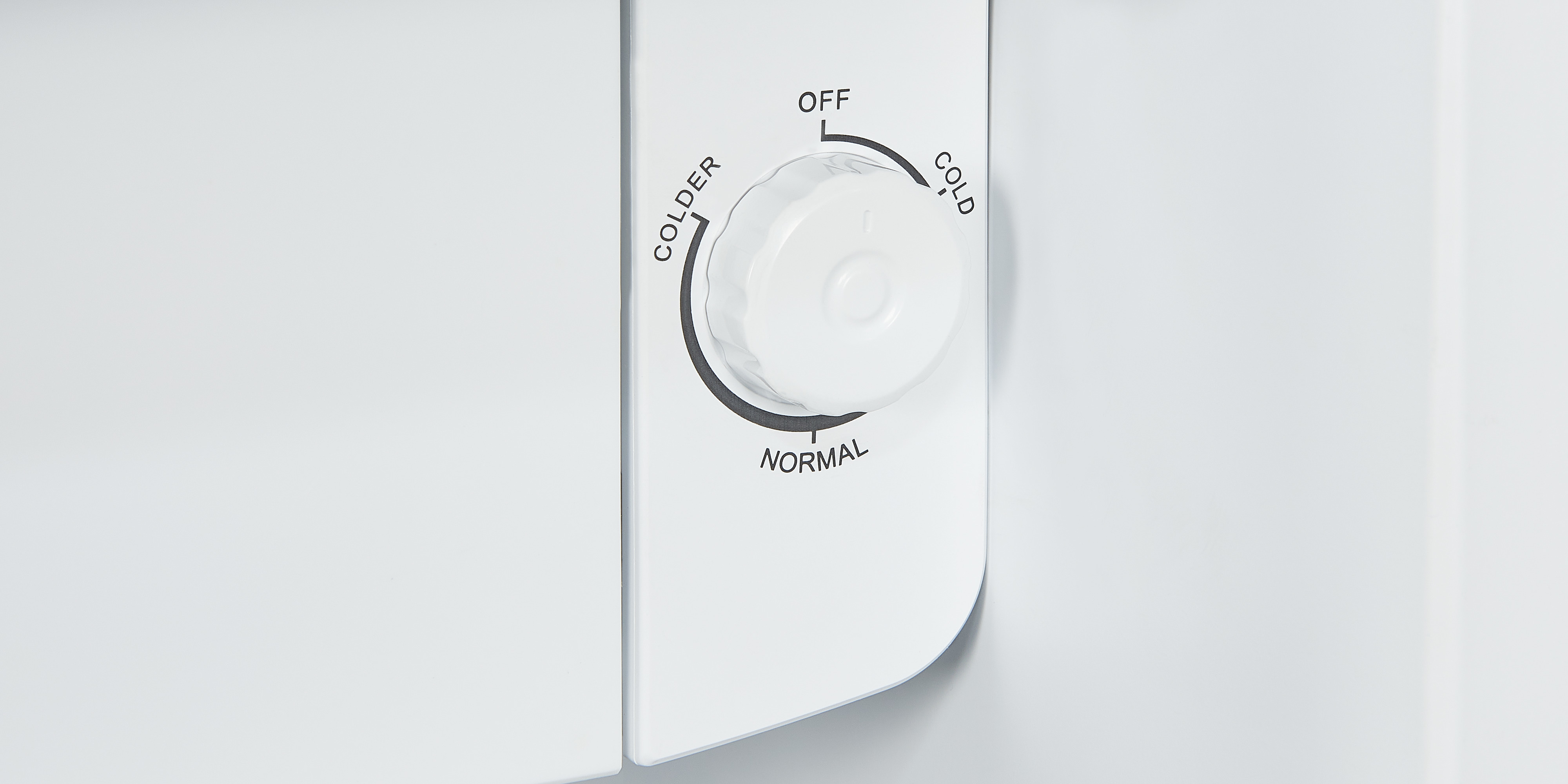 Primer plano de una perilla de control de refrigerador blanca con ajustes: más frío, frío, normal y apagado.