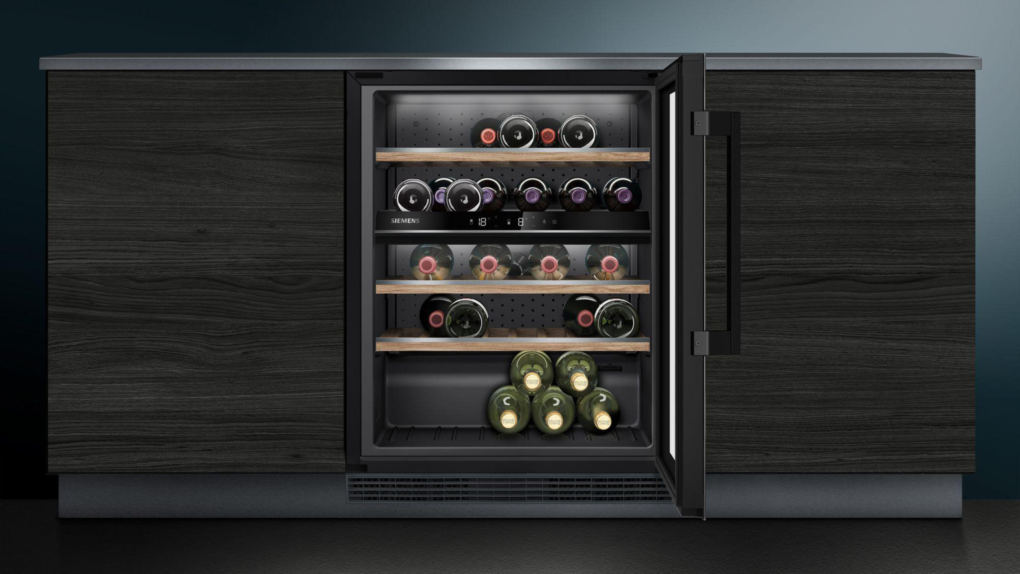Wine cooler with bottles on shelves. It is built into a dark wood cabinet.