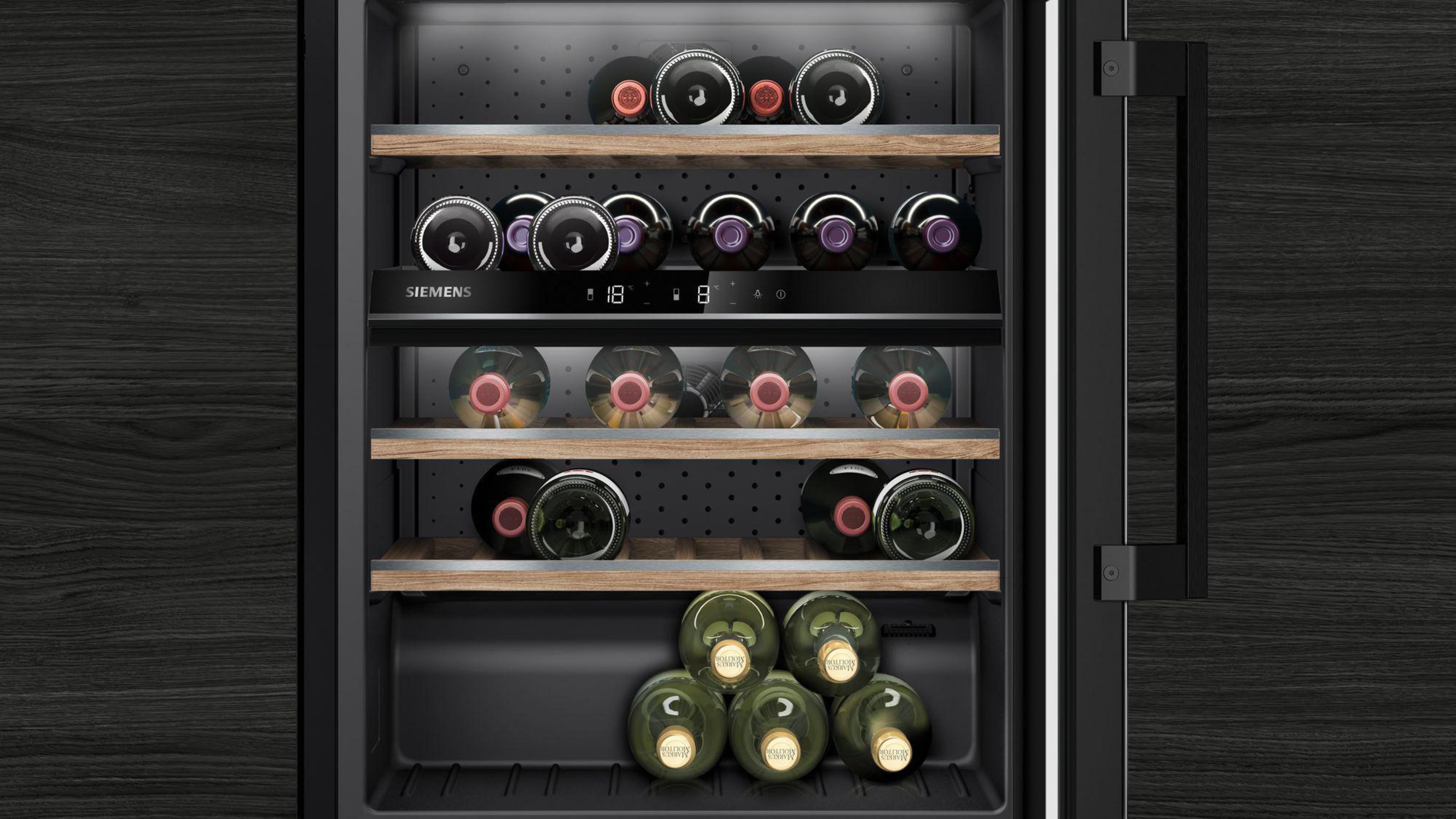 Wine fridge with bottles inside, wooden shelves and dark background.