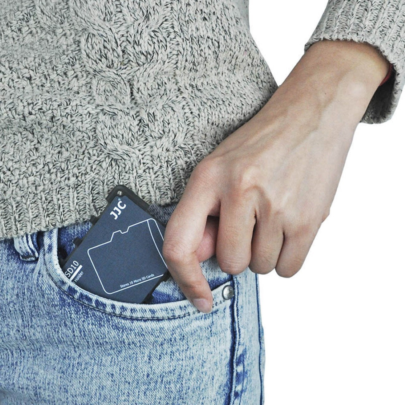 Hand steckt Speicherkarte in die Tasche. Blaue Jeans.