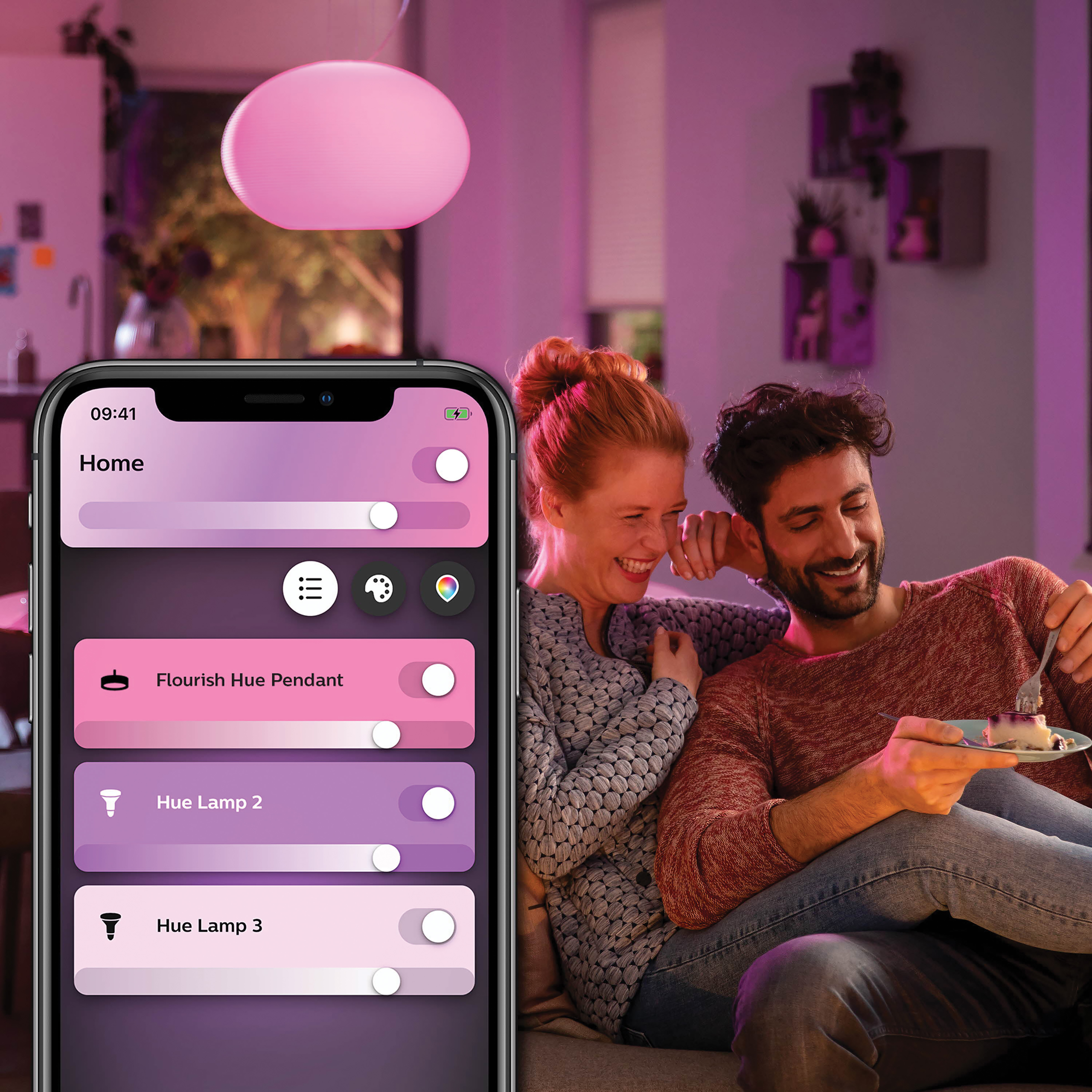Para używa telefonu do sterowania światłem. Ekran pokazuje sterowanie inteligentnym domem. Różowa lampa wisząca.