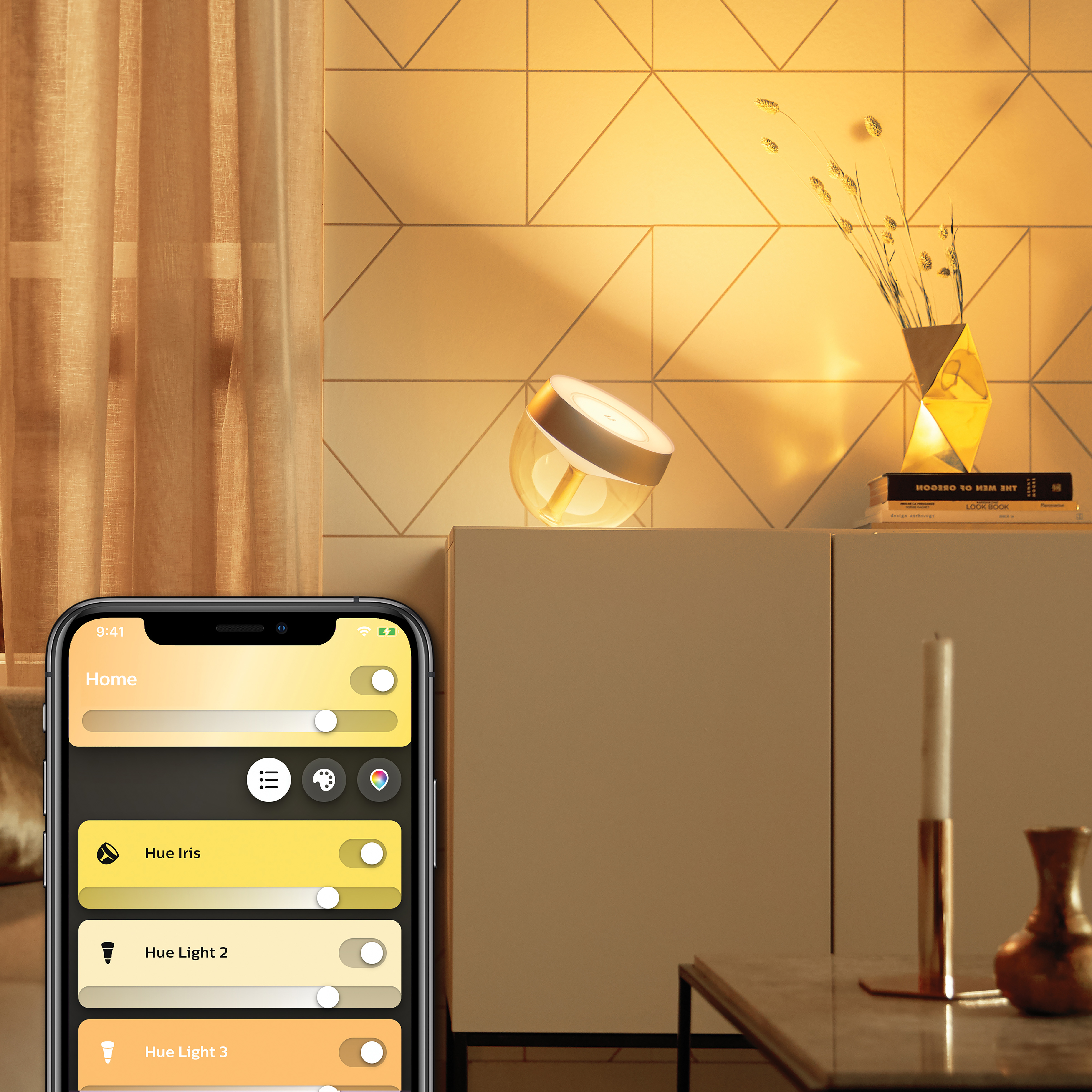 Eine Lampe mit App-Oberfläche auf einem Telefon. Auf einem Schrank, mit Vase und Kerze.