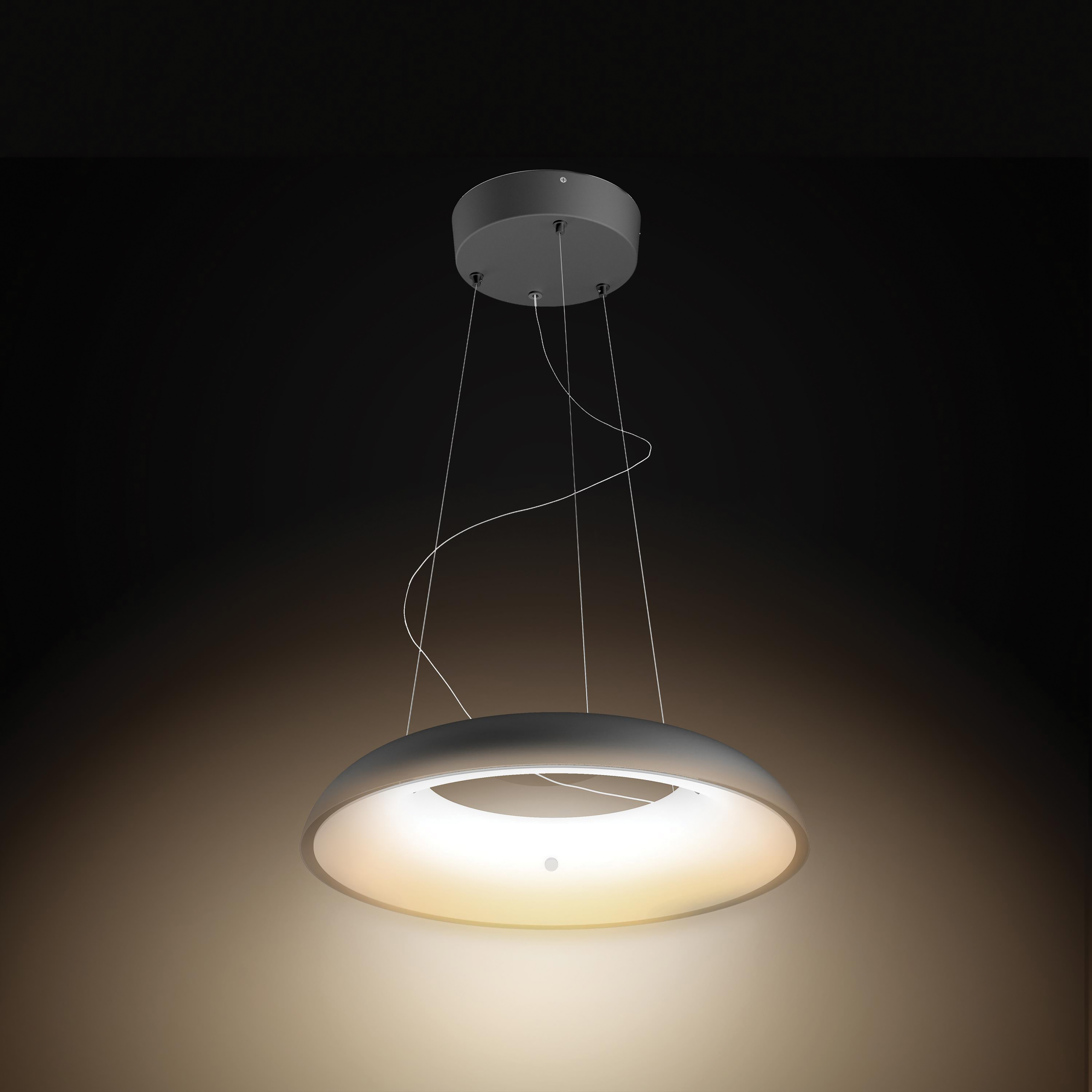 Une lampe suspendue circulaire moderne pend du plafond, avec une lumière chaude et brillante.