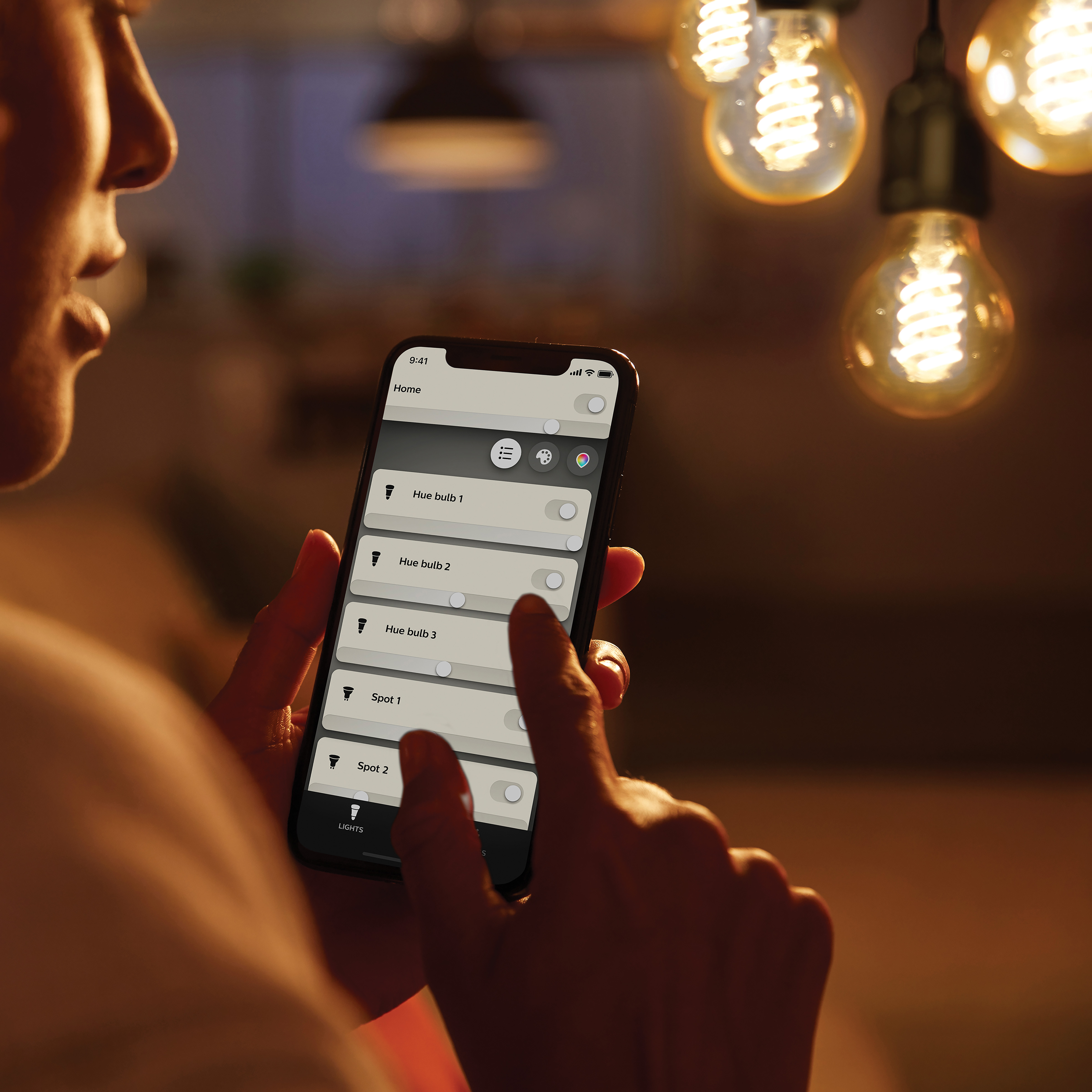 Osoba używa telefonu do sterowania inteligentnymi żarówkami. Żarówki wiszące, kontrola oświetlenia.