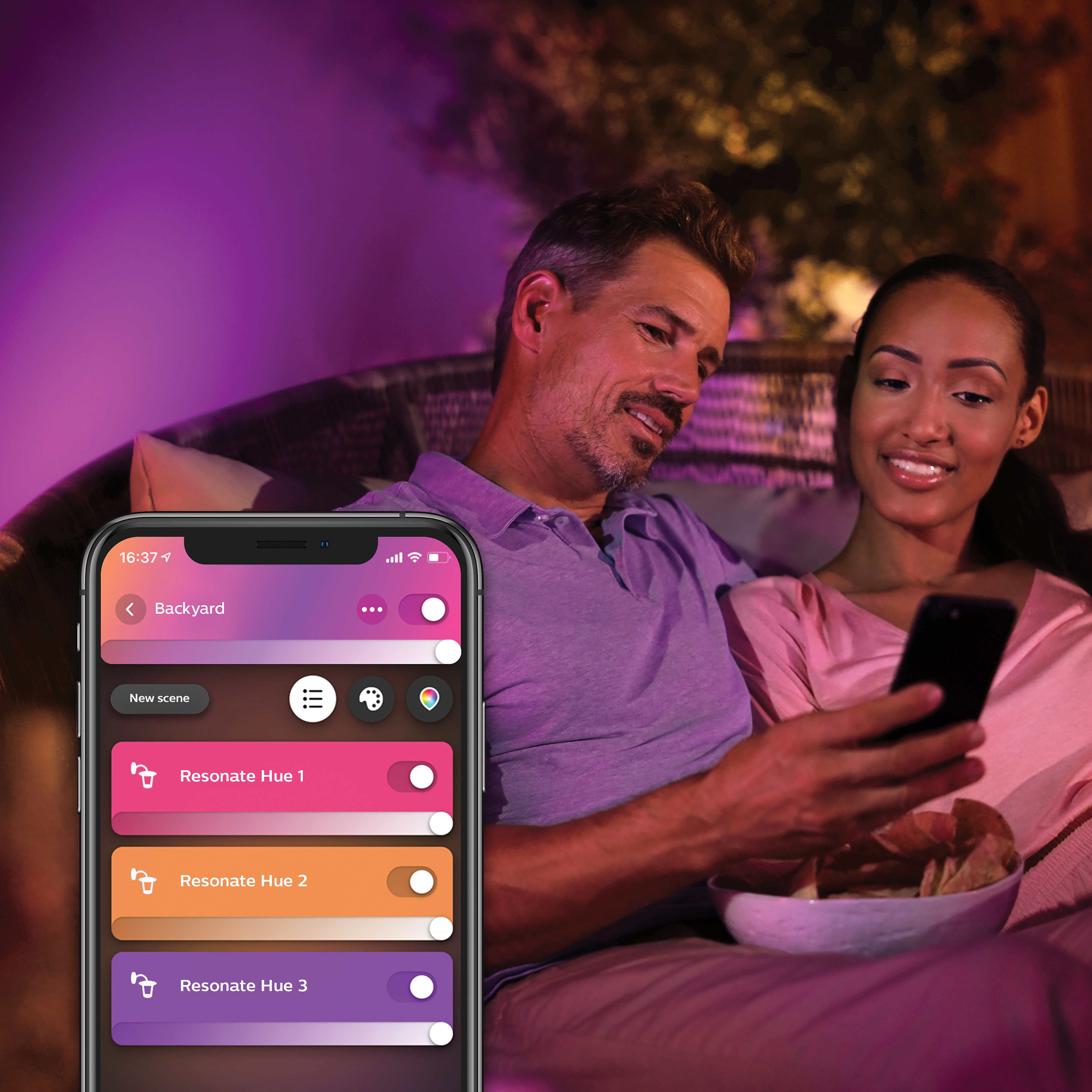 Couple regardant un téléphone affichant une application de maison intelligente en extérieur.
