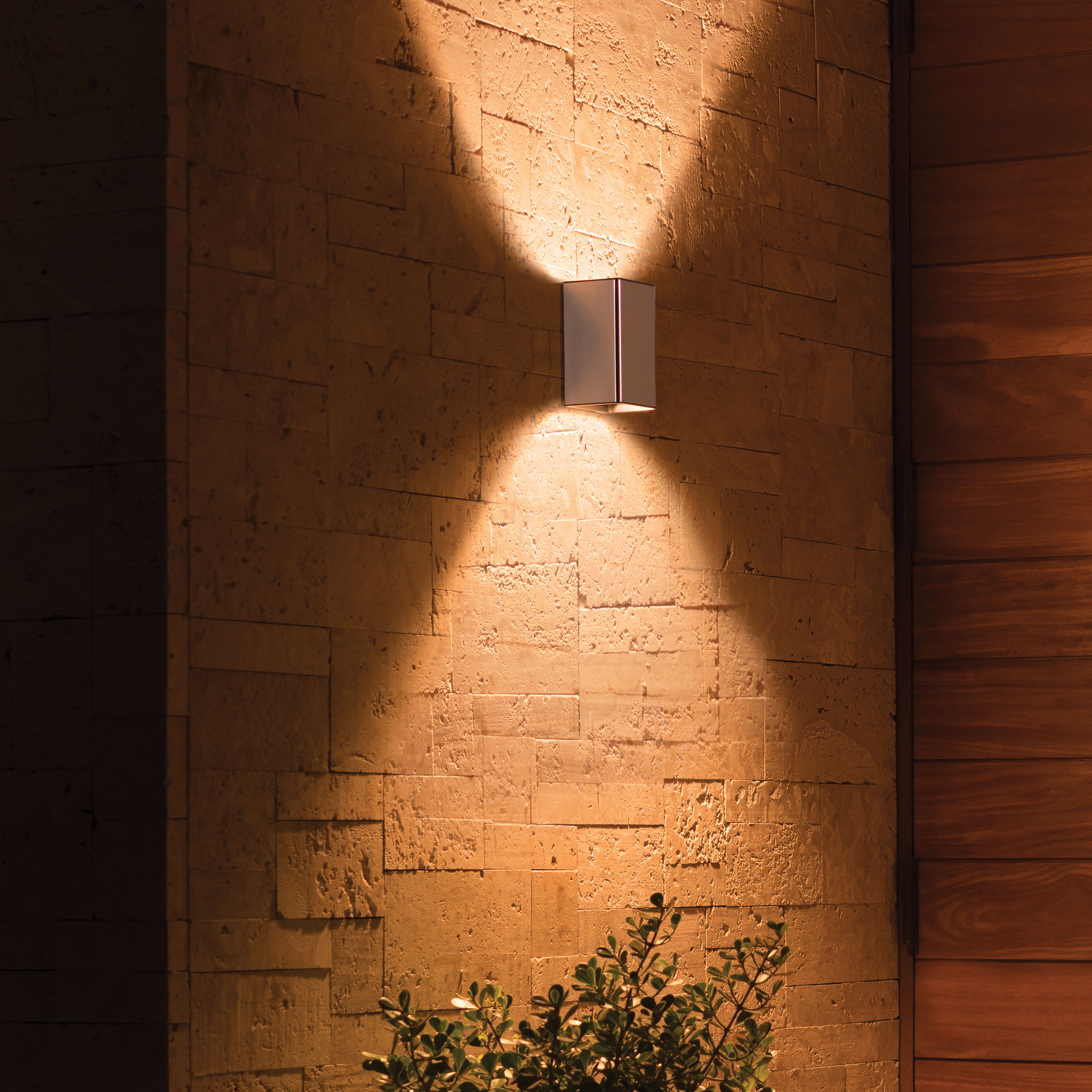 Un luminaire blanc sur un mur de briques, projetant une lumière chaude.