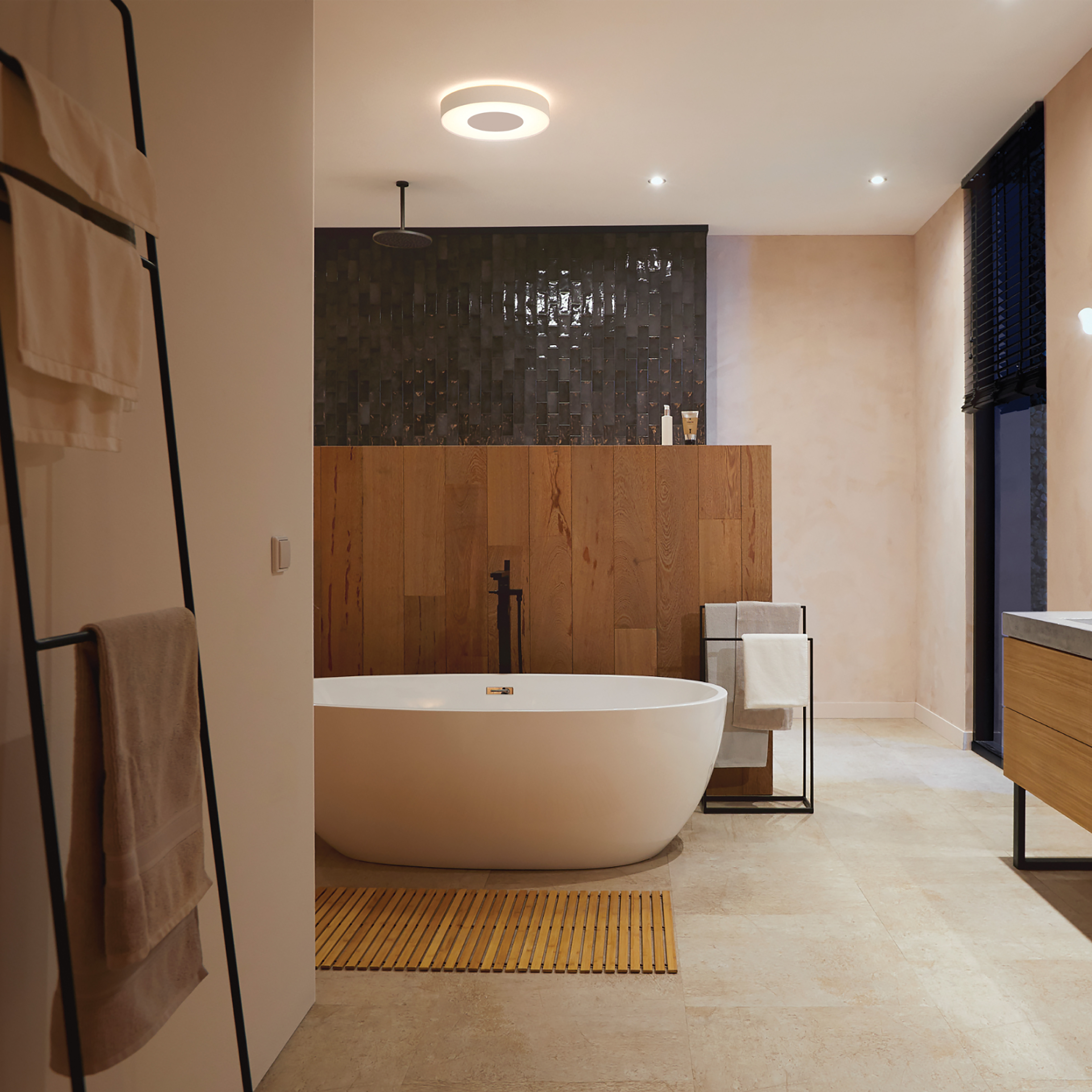 Łazienka z wanną, ręcznikami i oświetleniem sufitowym. Czarno-jasny design.