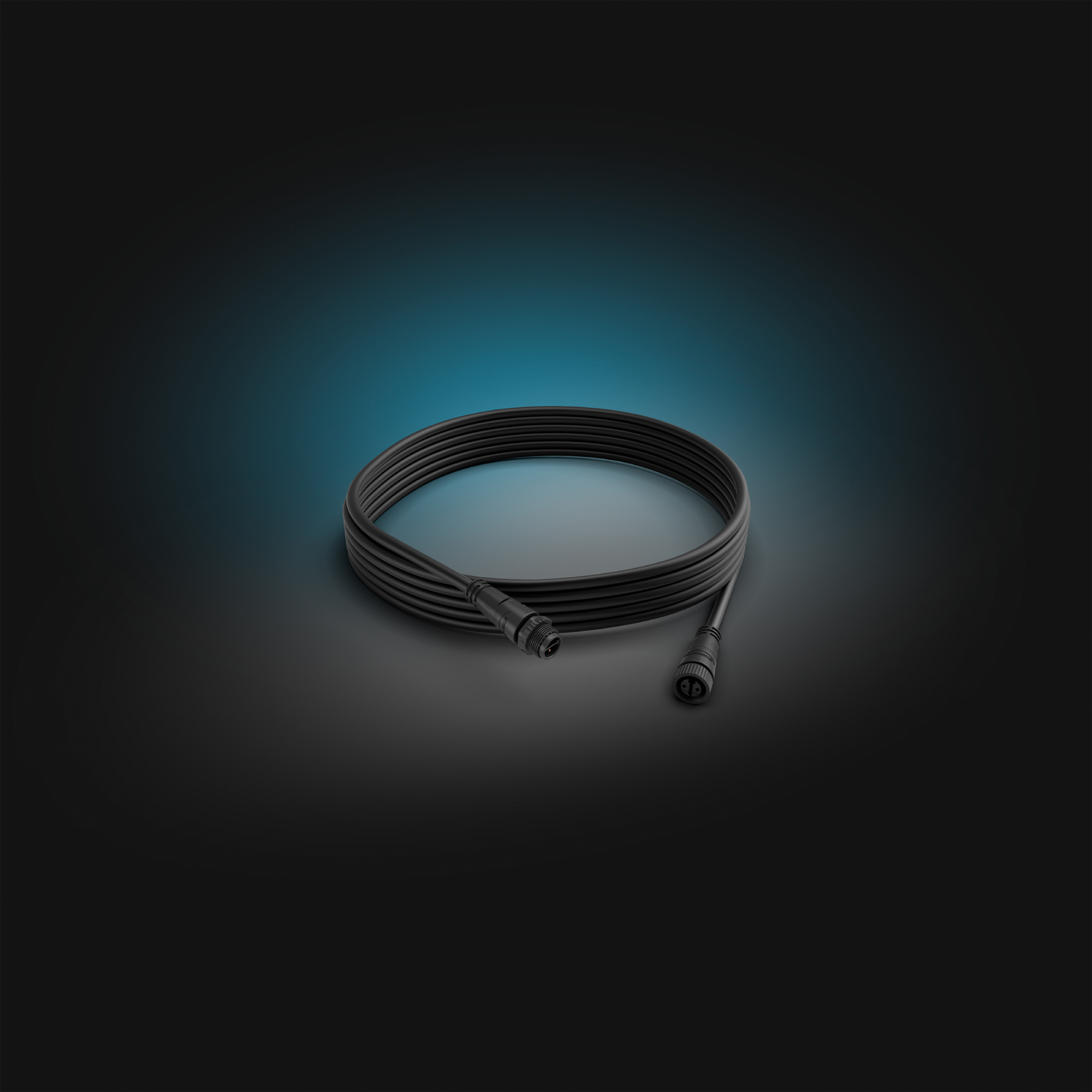 Gewickeltes schwarzes Kabel mit zwei Steckern. Das Kabel liegt auf dunklem blauem Hintergrund.