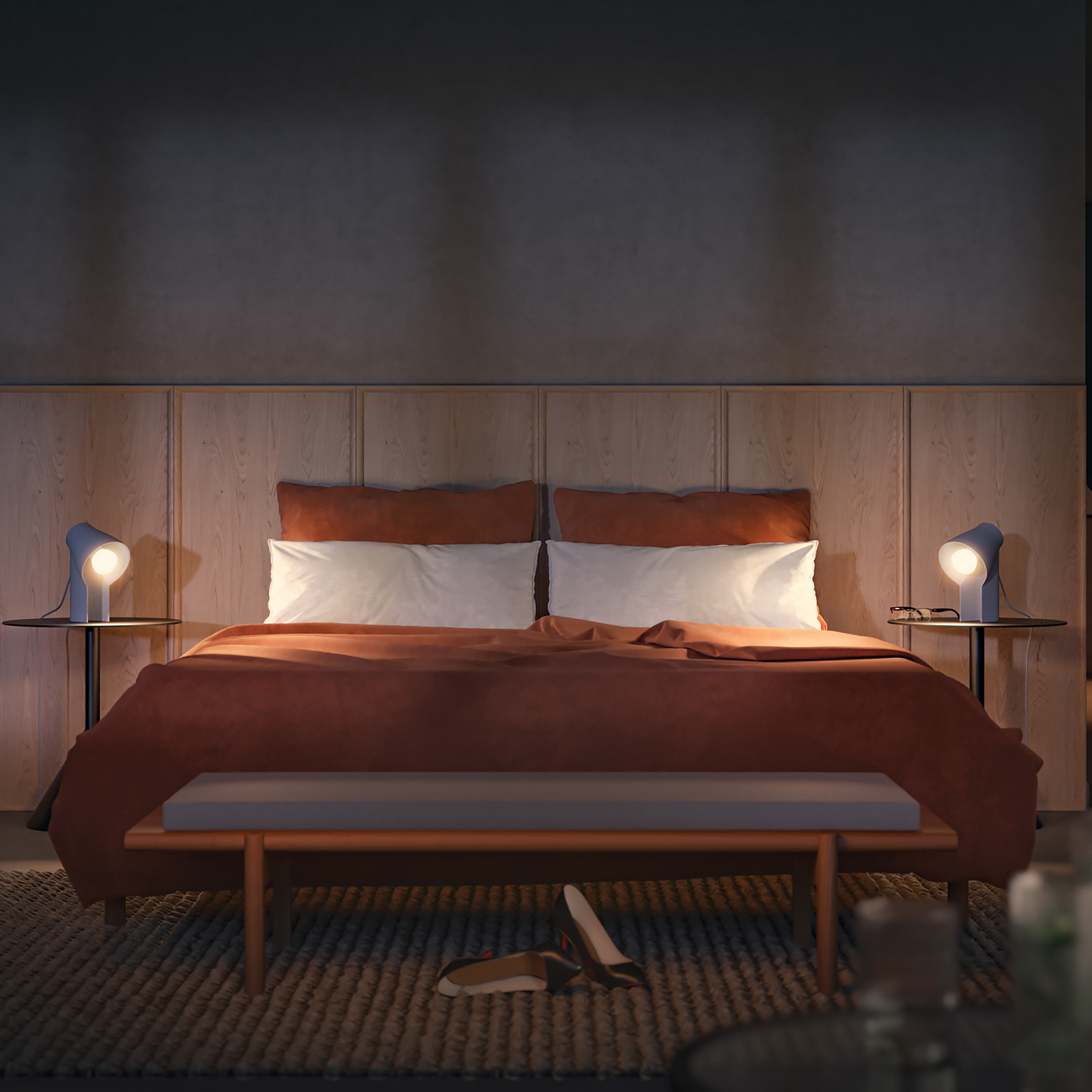 Scena sypialni: łóżko z pomarańczową pościelą, dwie lampy na szafkach nocnych i ławka u stóp łóżka.