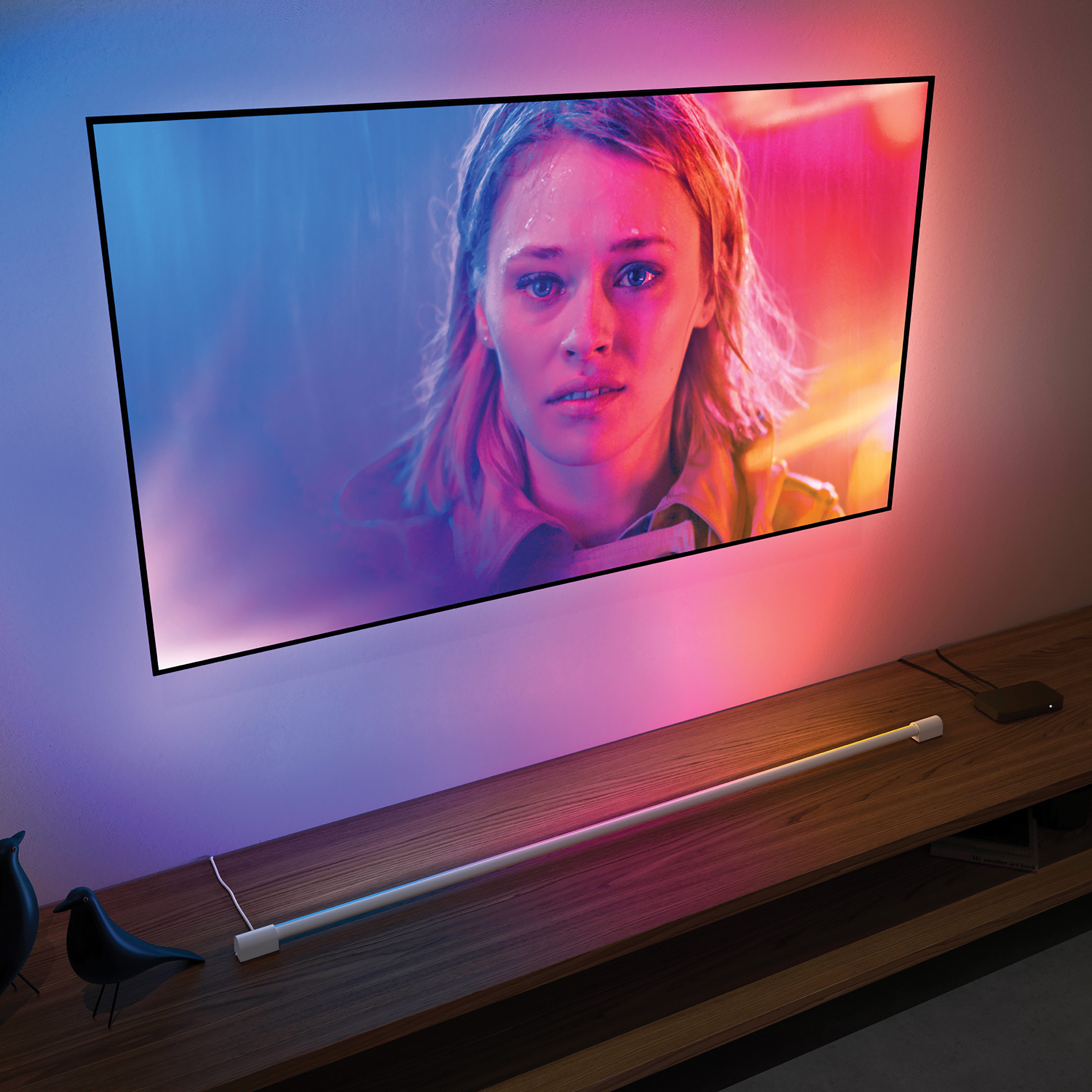 Frau auf einem Fernsehbildschirm mit farbigem Lichtbalken unter einem Holztisch.