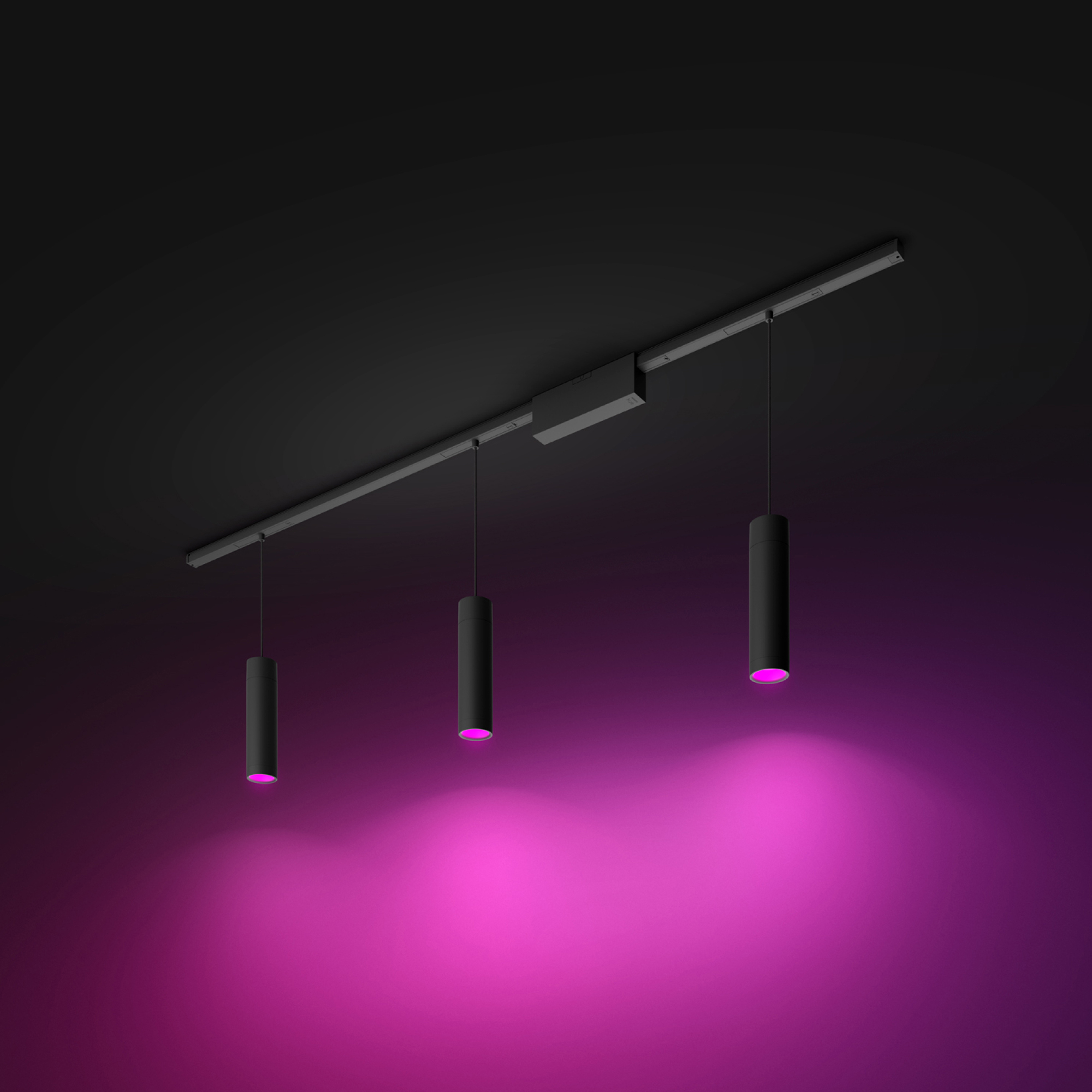 Trzy czarne cylindryczne światła wiszące na czarnej szynie, oświetlające różową powierzchnię.