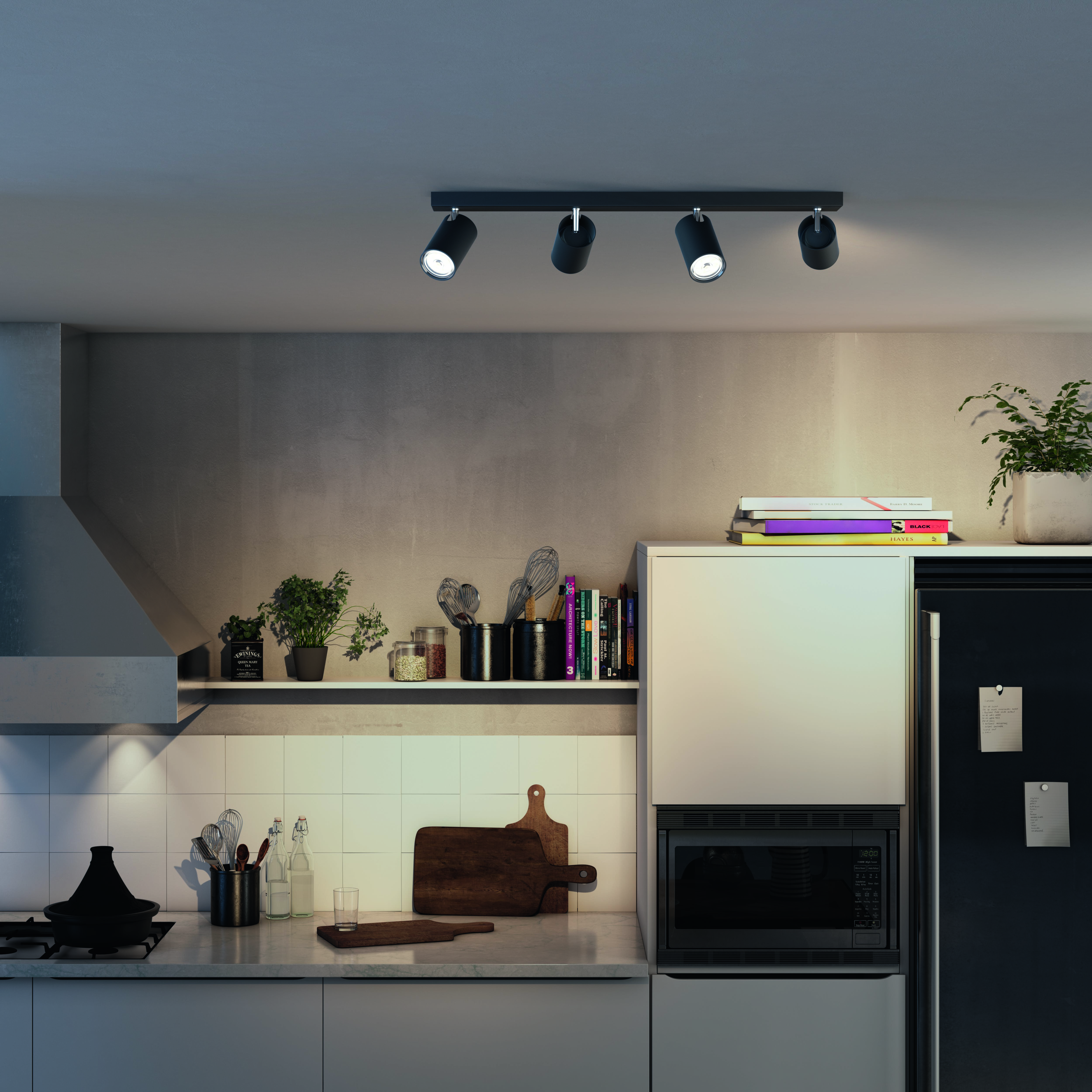 Cucina con faretti a soffitto. Include un forno a microonde, mensole con piante e utensili.