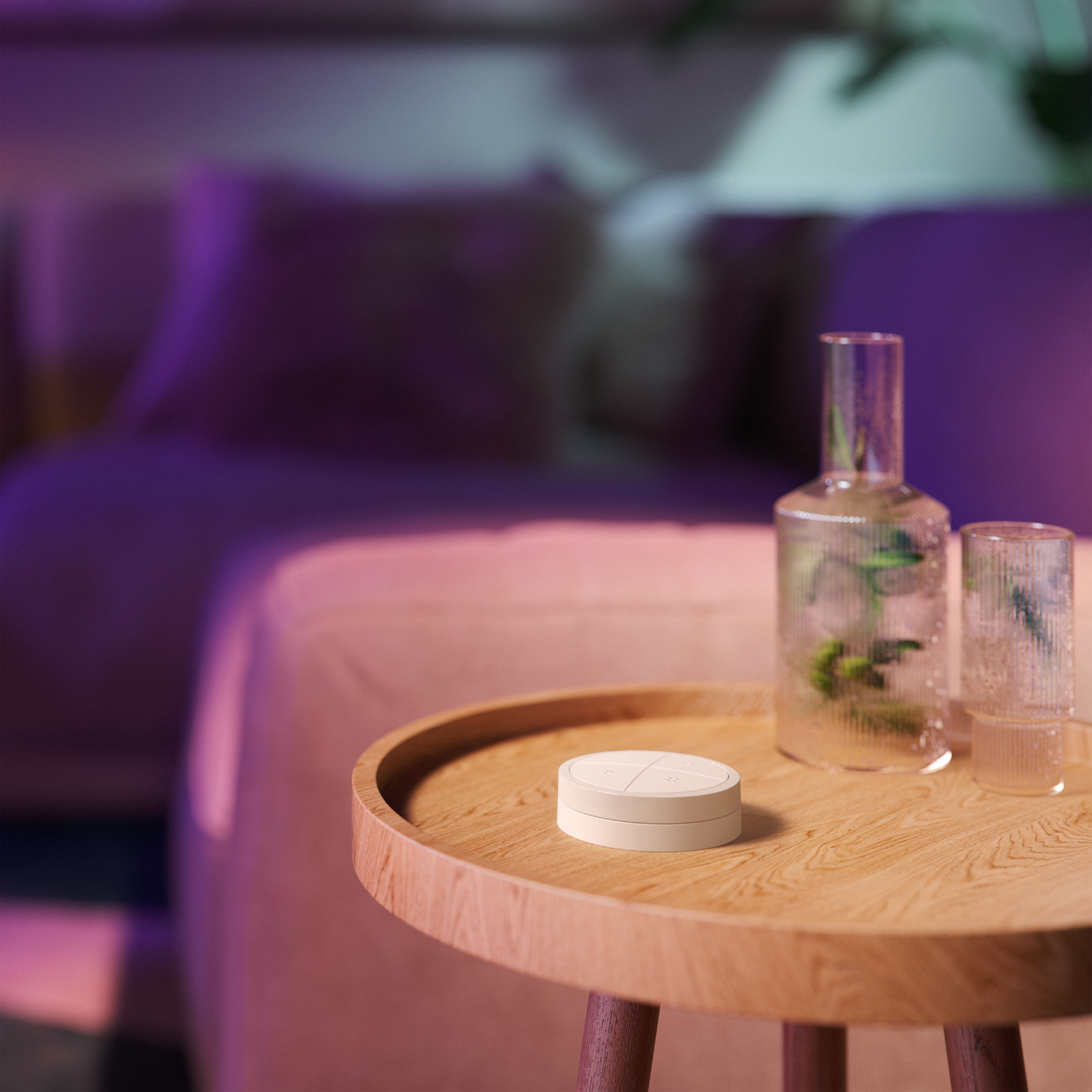 Mesa de madera con control remoto blanco, dos jarrones y sofá al fondo.