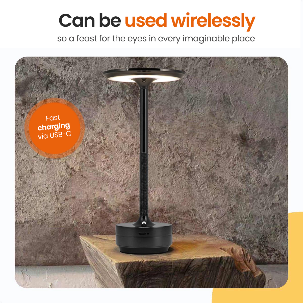 A black and silver lamp with a white light sits on a wooden block with a textured wall background.