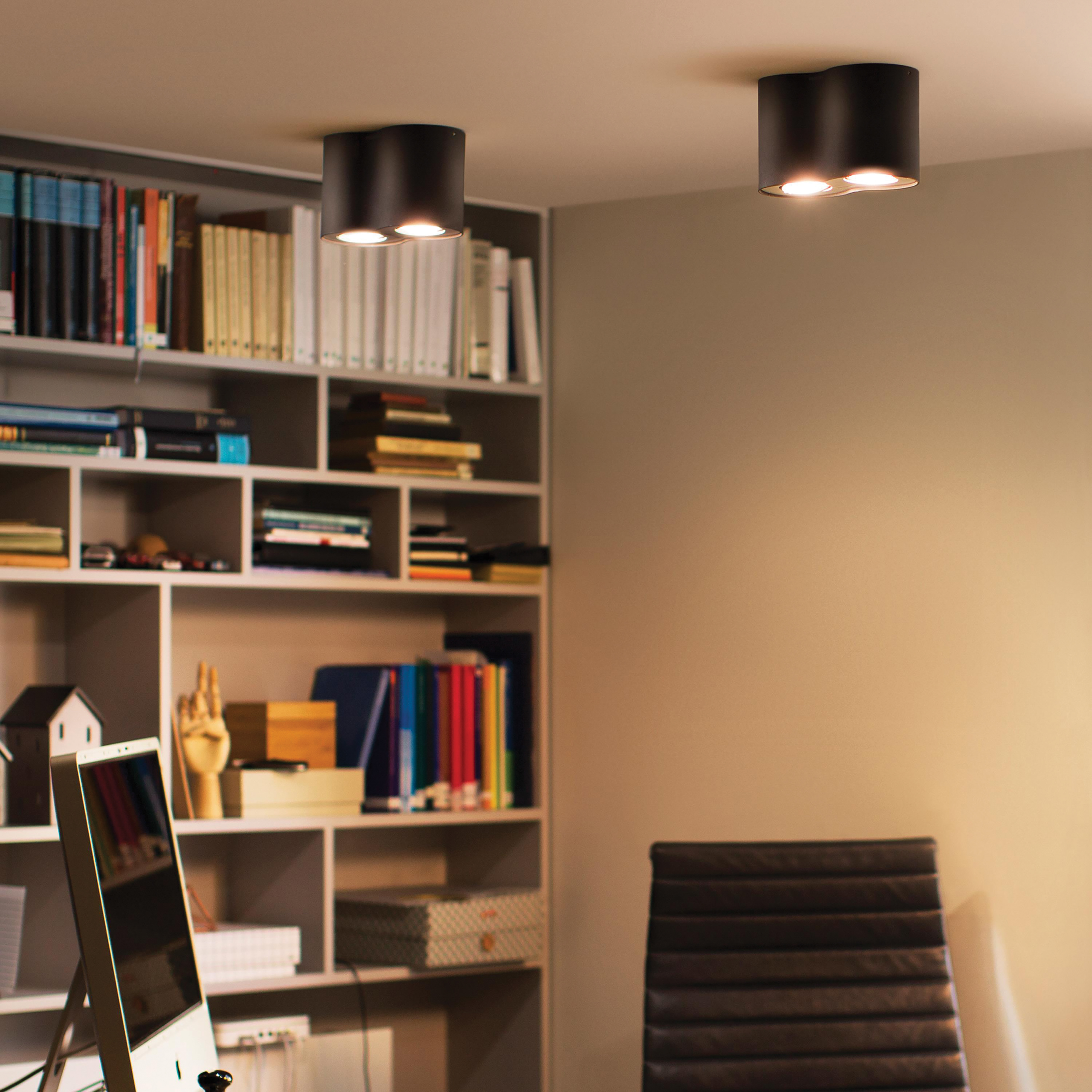 Dwa czarne światła sufitowe. Są wpuszczane, a tło przedstawia regał i krzesło.