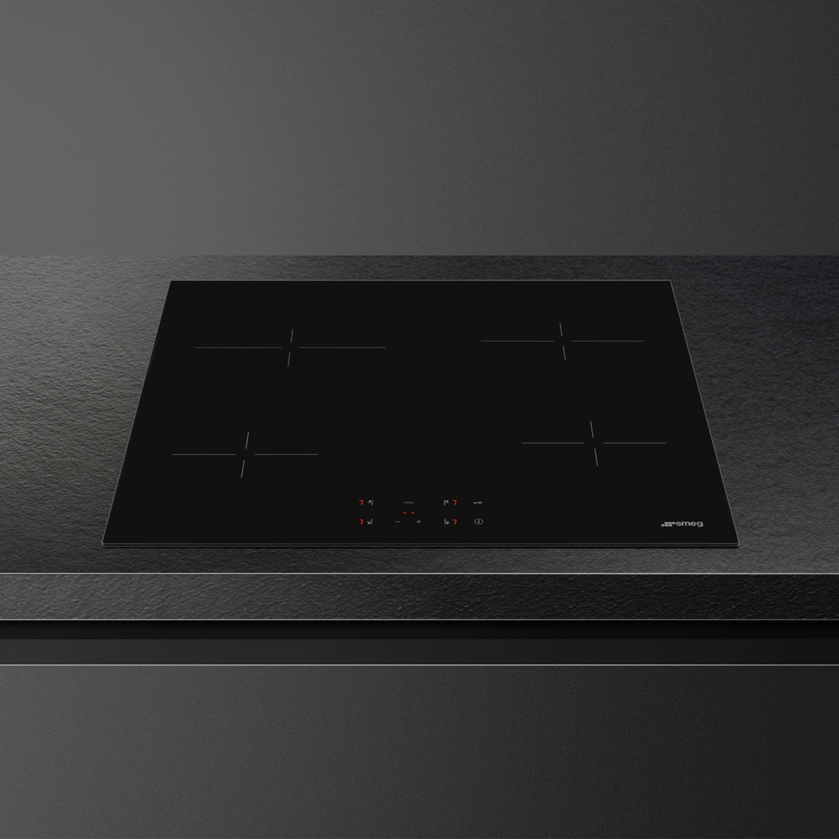 Vista cenital de una placa de inducción negra sobre una superficie oscura con el logotipo de Smeg.