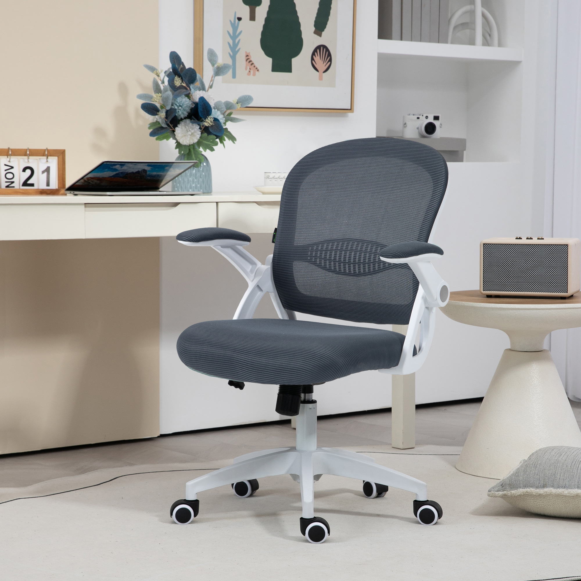 Una sedia da ufficio grigia con schienale in rete e telaio bianco, in un moderno ufficio domestico, con scrivania e decorazioni.