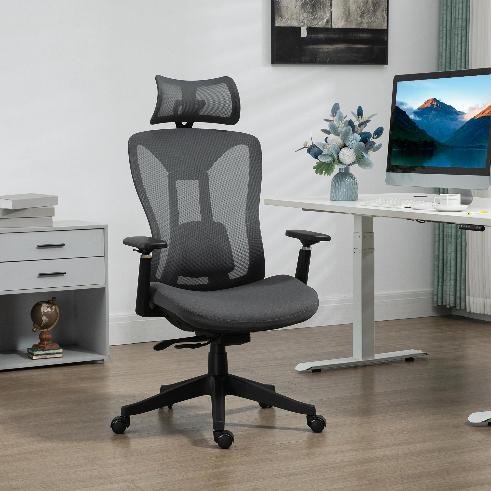 Ein grauer Bürostuhl mit Kopfstütze in einem modernen Homeoffice-Setup mit Schreibtisch und Dekor.