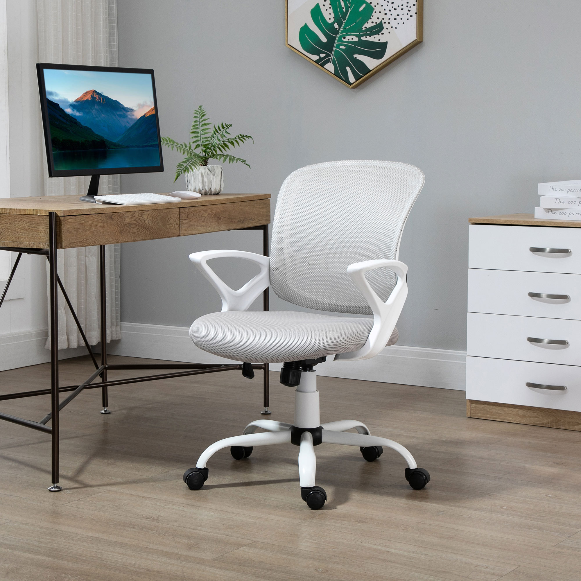 Una sedia da ufficio con telaio bianco e schienale in rete grigia, in un ufficio domestico con una scrivania.