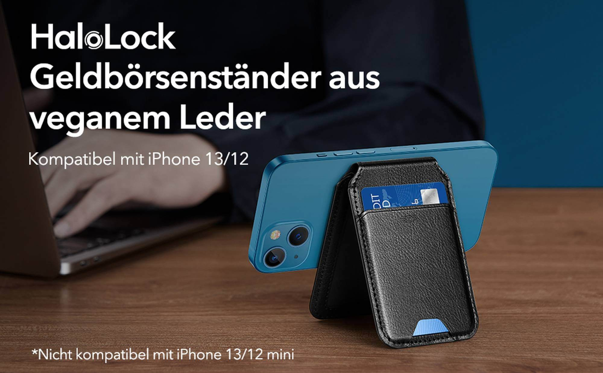 Ein schwarzes Telefon mit Kartenhalter steht auf einem Tisch. Im Hintergrund sind ein Laptop und eine Person zu sehen.