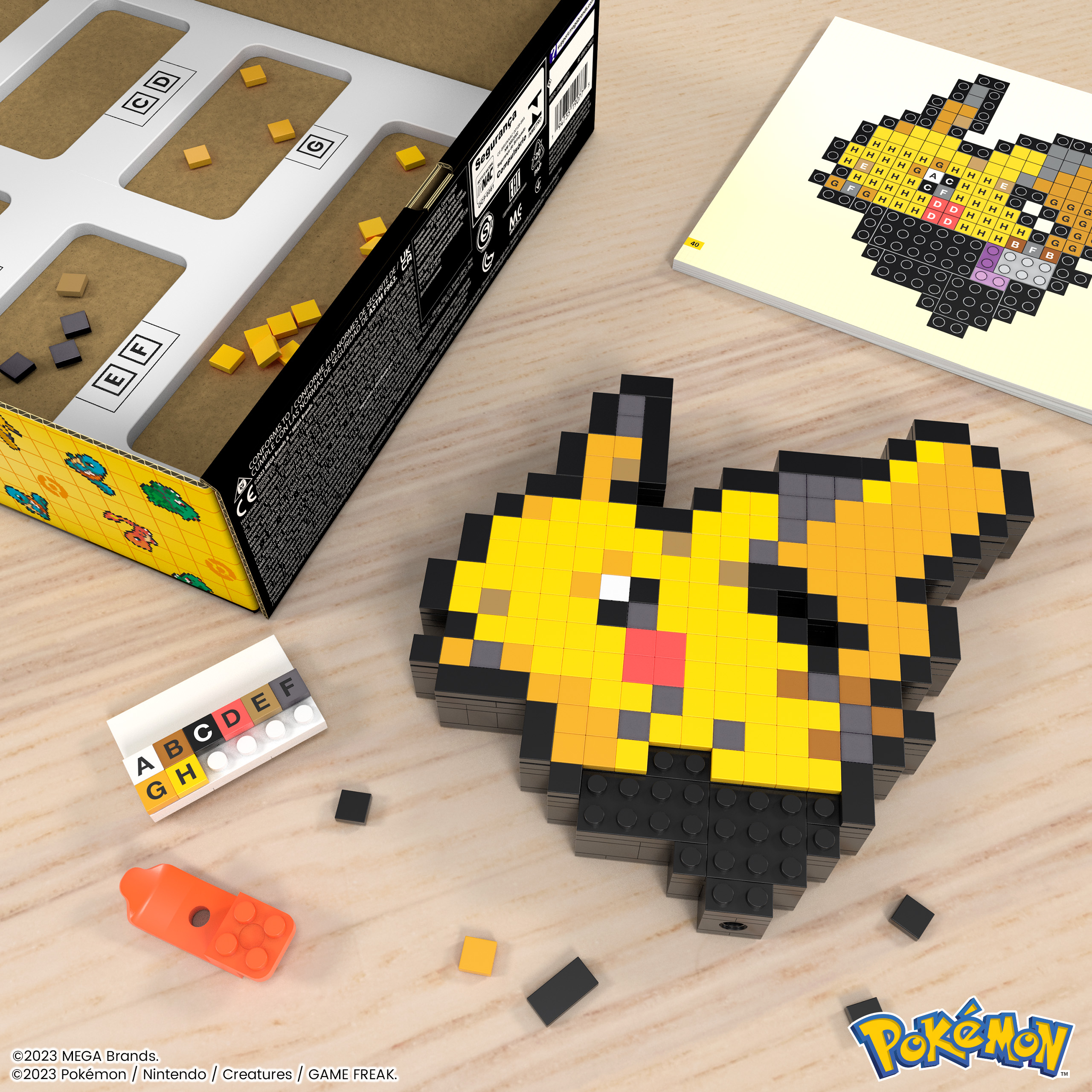 Art pixel de Pikachu fait de blocs, avec une boîte de blocs et un guide. Surface en bois.