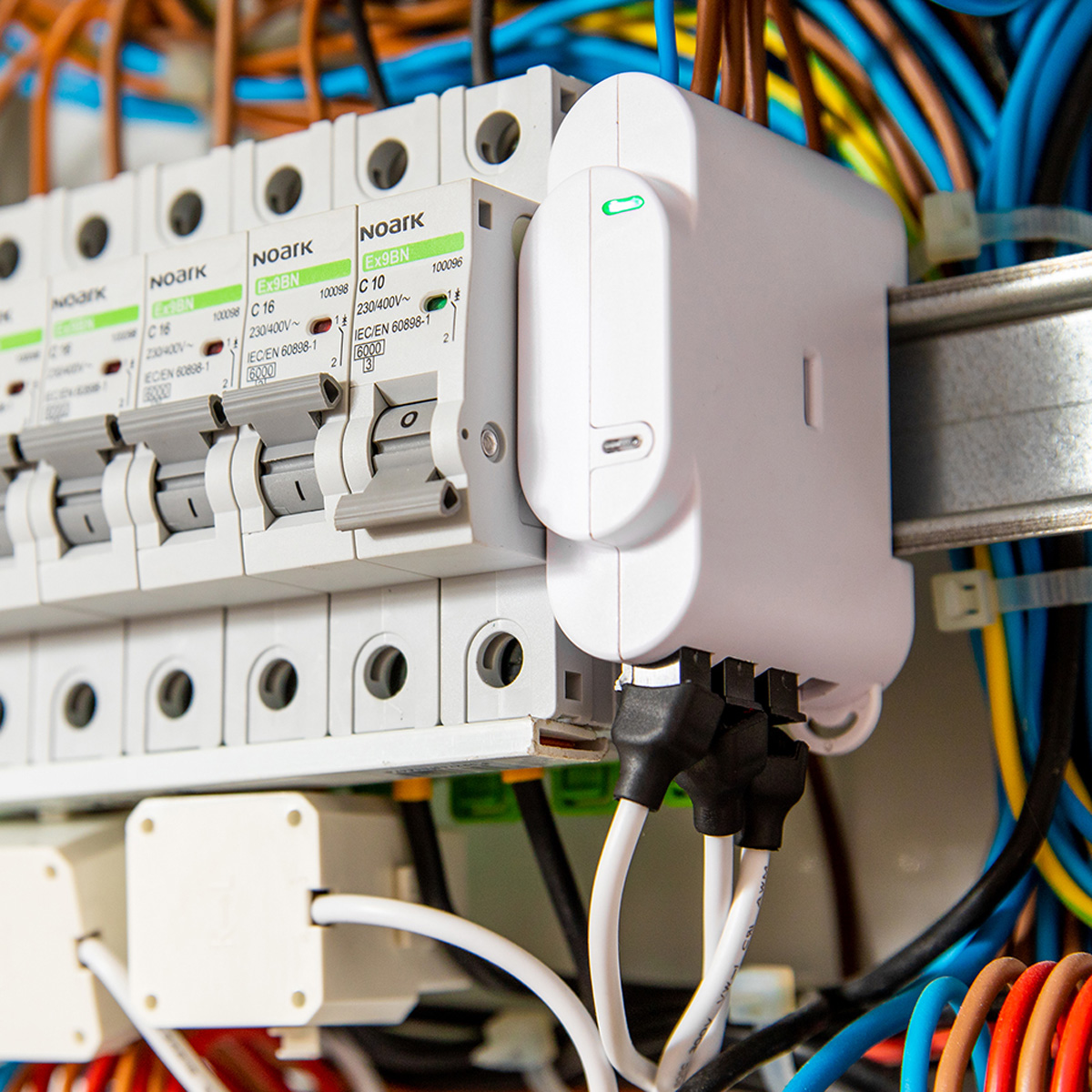 Panel eléctrico con componentes blancos y cables de colores. Primer plano. El fondo está borroso.