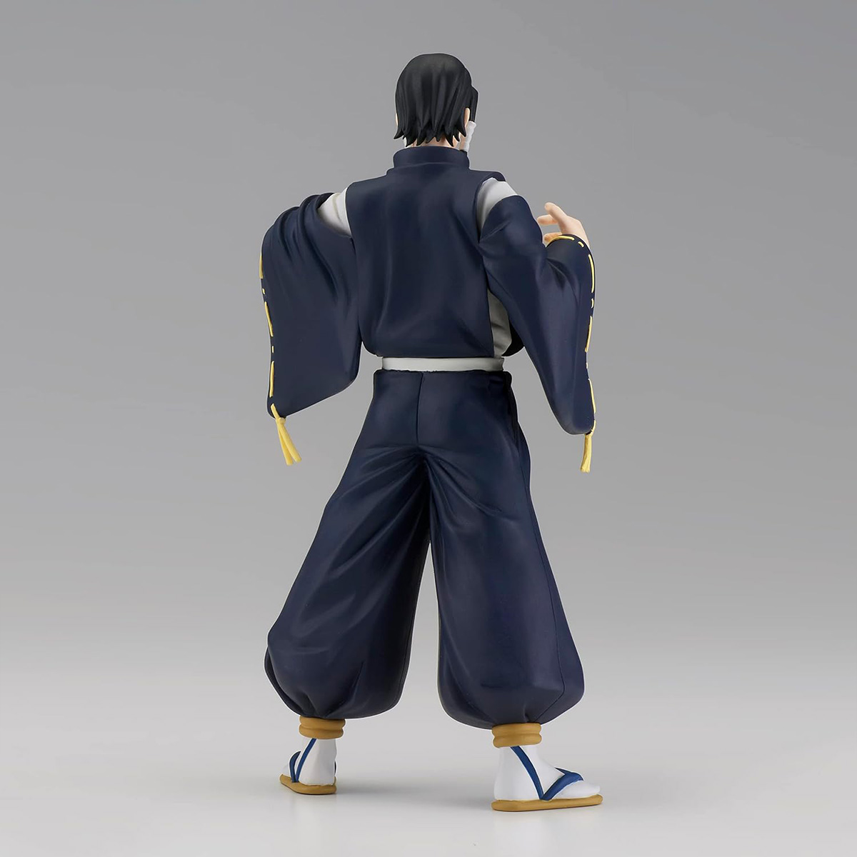 Anime-Figur, Mann in schwarz-weißem Outfit, Rückansicht. Lange Ärmel, schwarze Hose, weiße Schuhe.