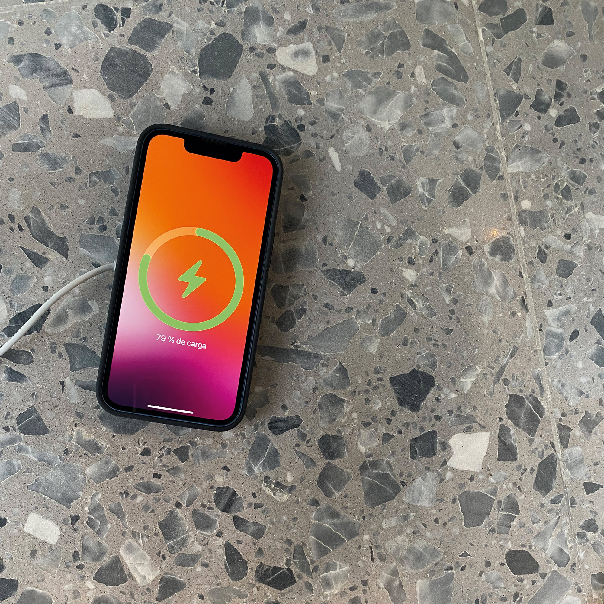 Un teléfono cargando en una superficie moteada, el indicador muestra 79%.