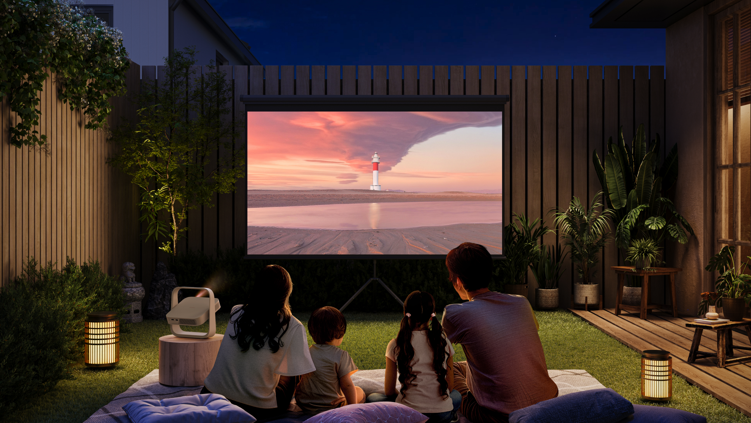 Rodzina oglądająca film na ekranie na podwórku w nocy.