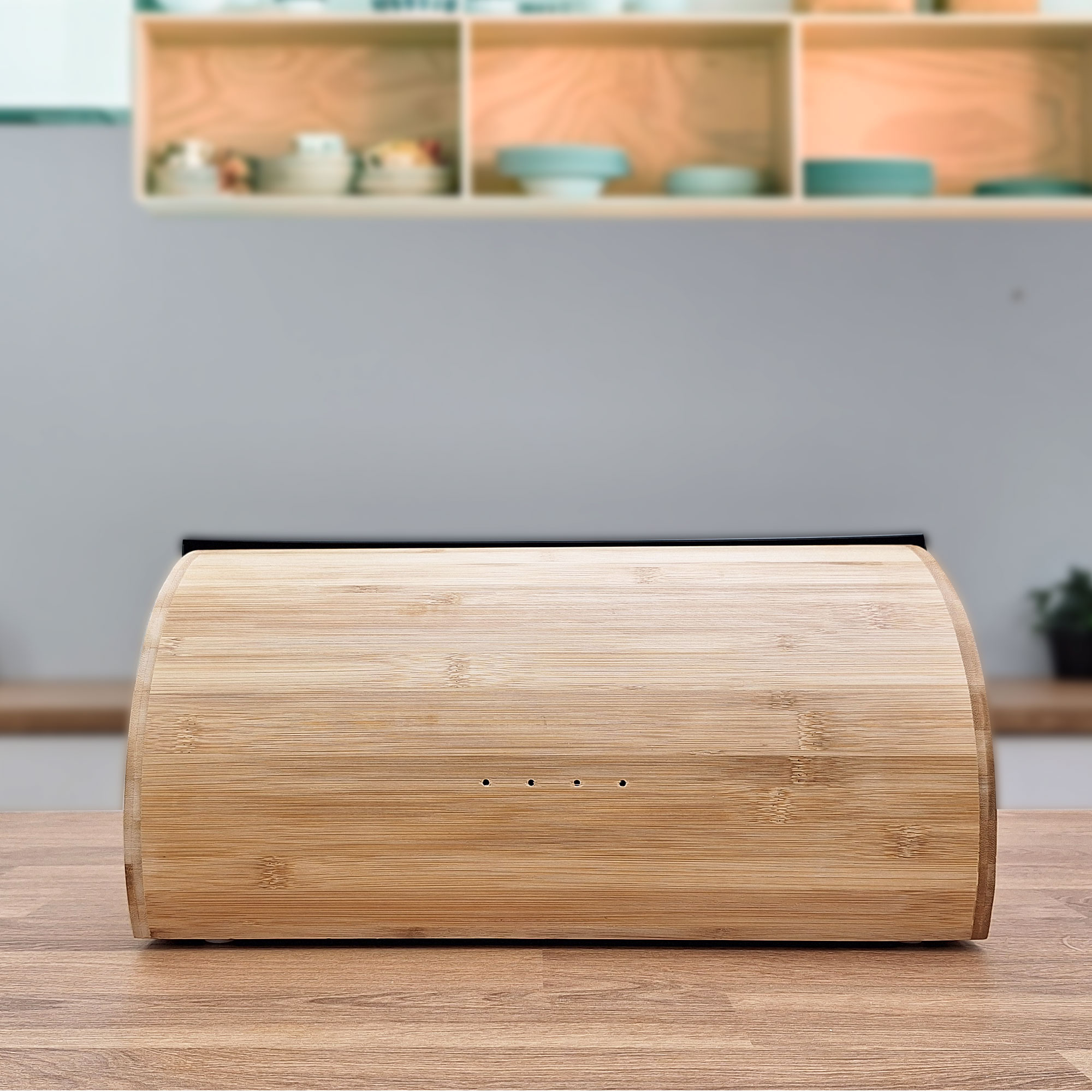 Panera de madera sobre mesa madera, frente a cocina clara. Cocina desenfocada.