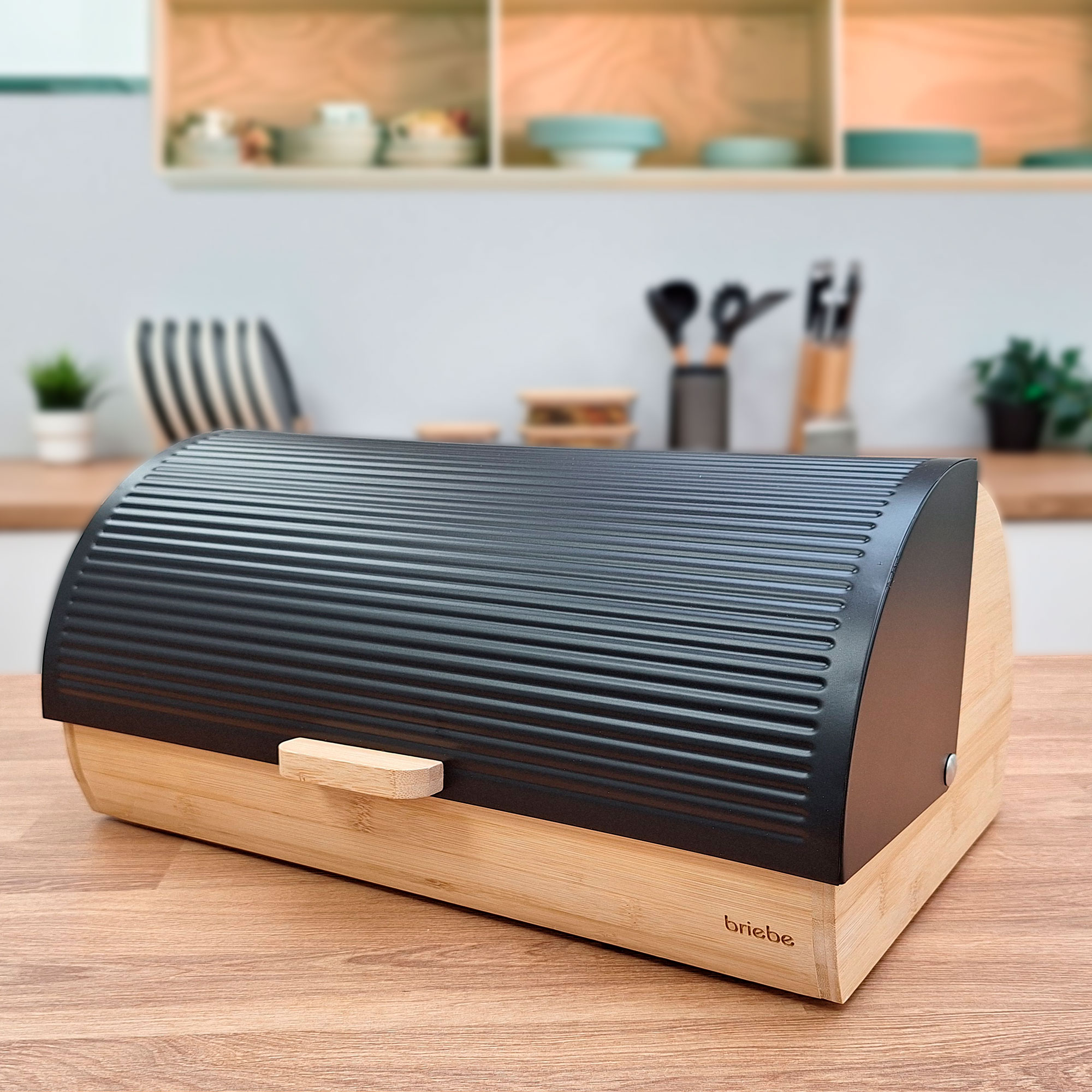 Caja de pan negra y madera sobre mesa de madera en ambiente de cocina.