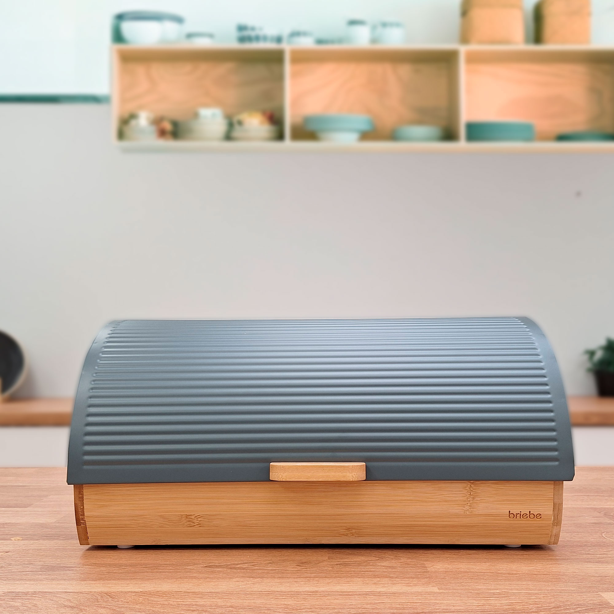 Caja de pan de madera cerrada. Tapa gris y base de madera, en mesa de madera. Fondo de cocina.