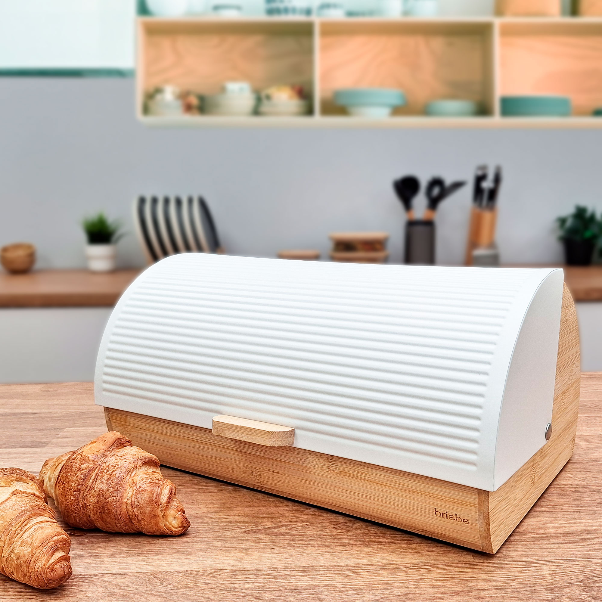 Caja de pan blanca y cruasanes en mesa de madera en ambiente de cocina.