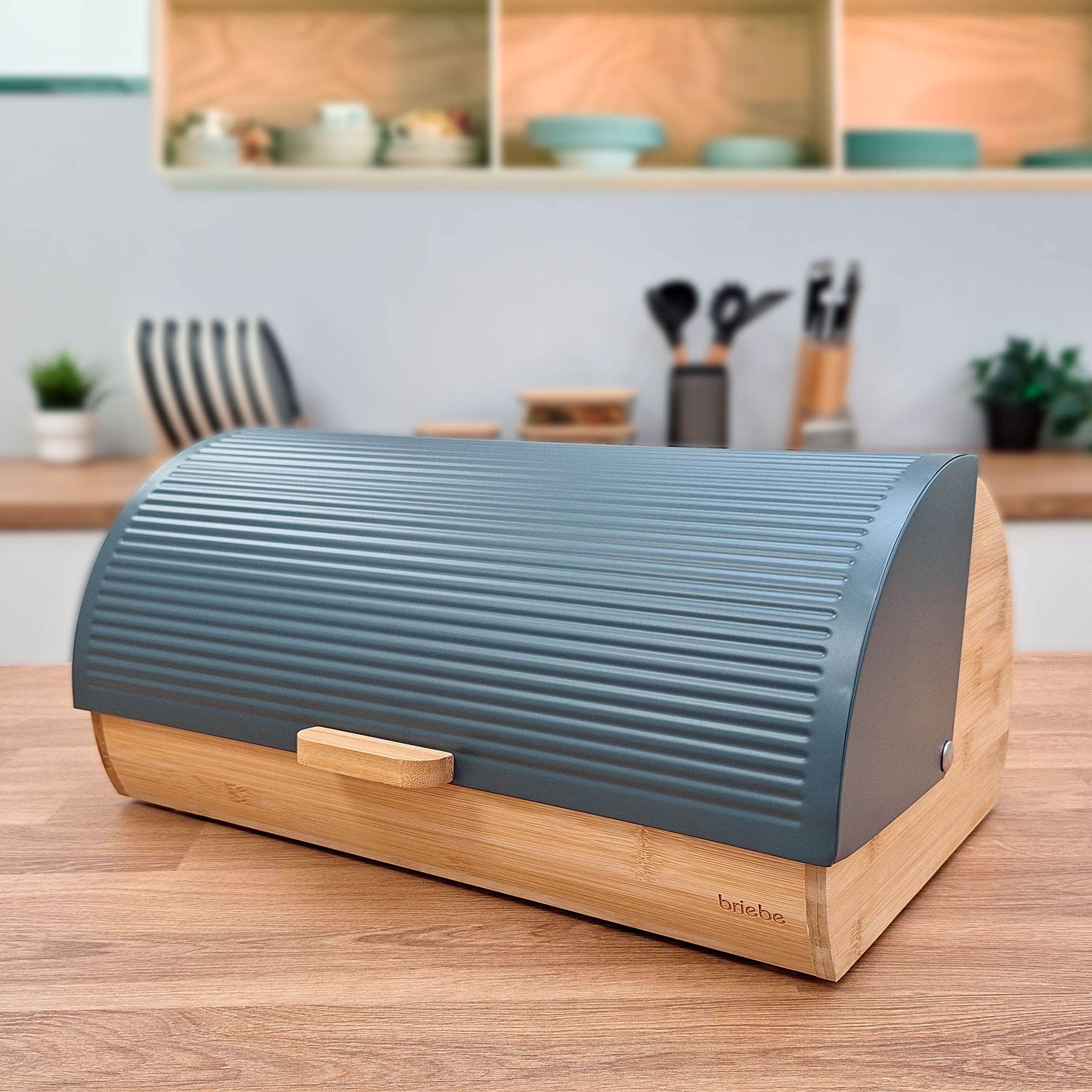 Una panera gris sobre madera. Tiene base de bambú y tapa arqueada y acanalada.