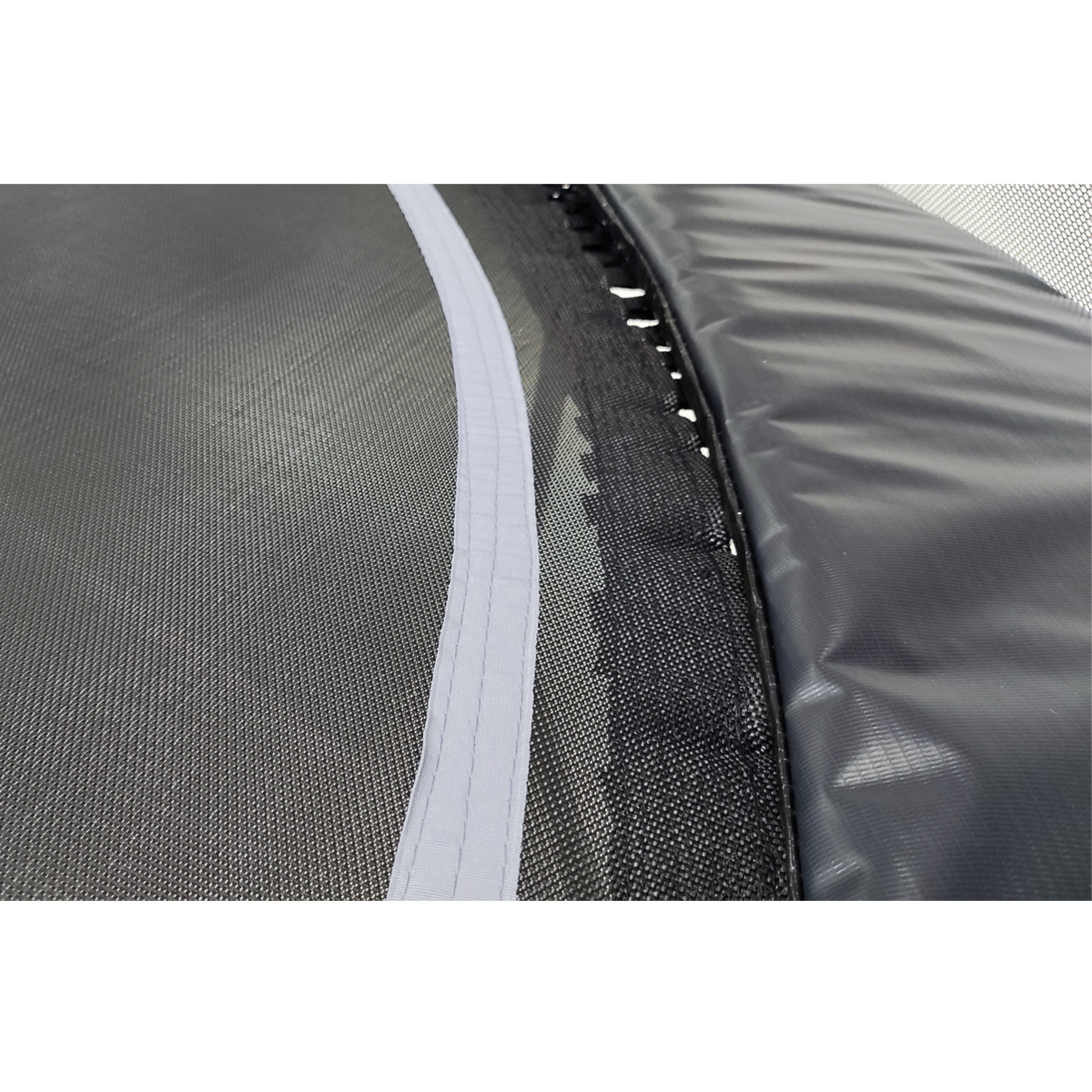 Gros plan sur le filet d'un trampoline, bord blanc, cadre noir et ressorts noirs.