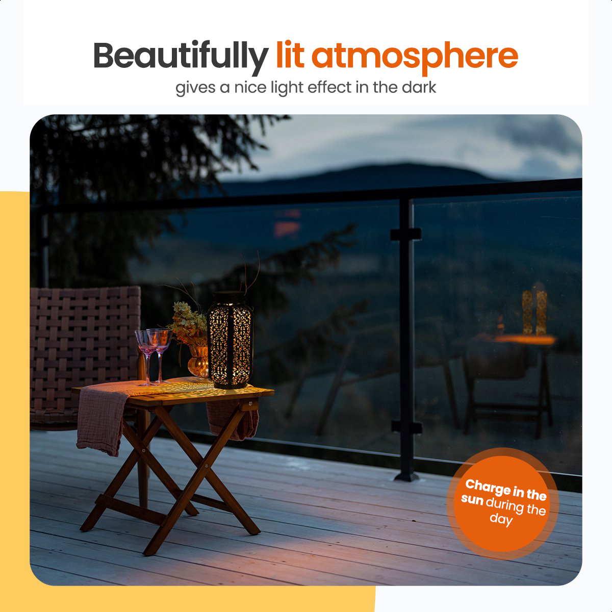 Outdoor scene at night with a lit lantern, two glasses, and a chair on a deck with a mountain view.