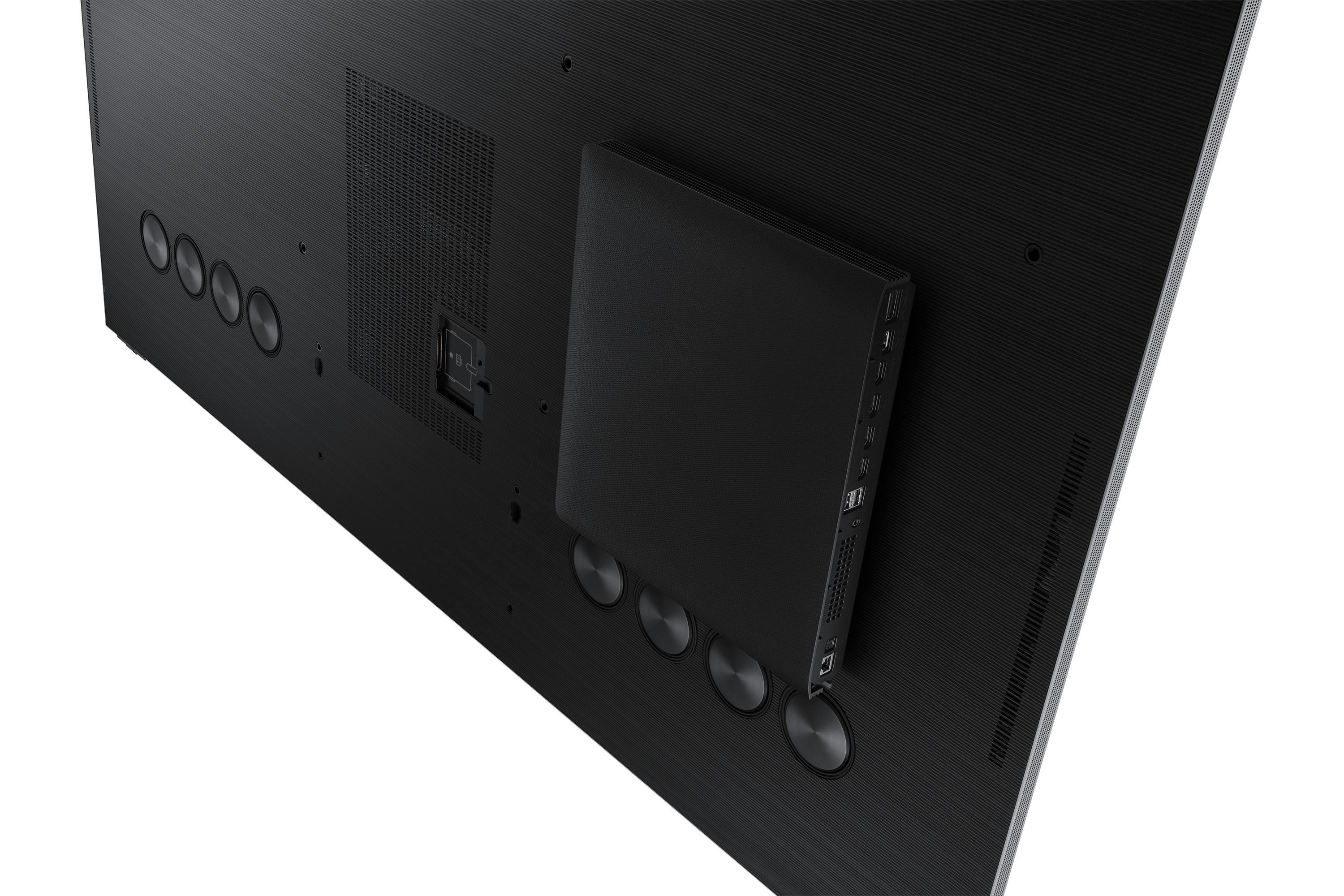 Parte trasera de un televisor negro grande con puertos y una caja negra conectada. Fondo blanco.