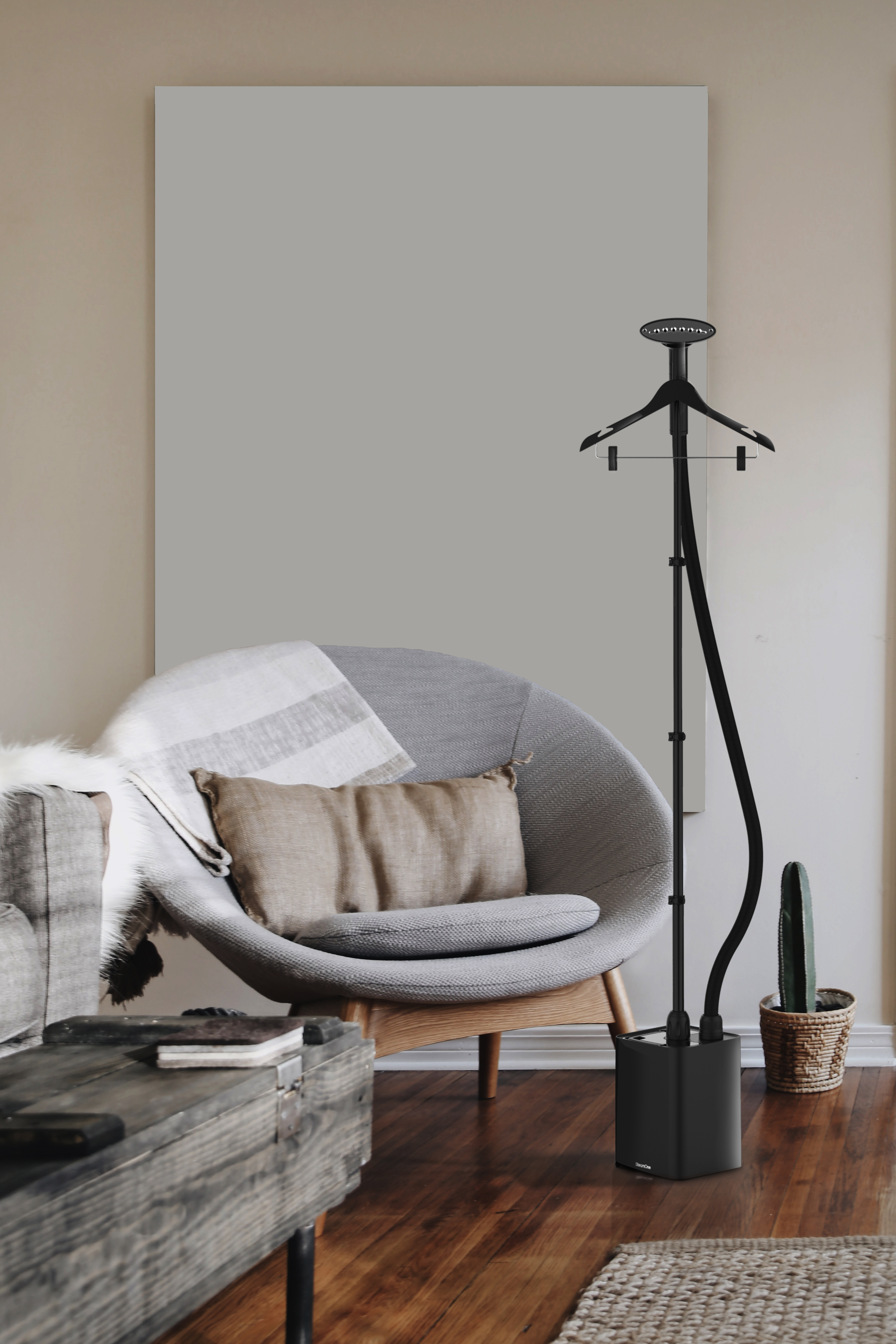 A room with a chair, a steamer, and a side table. A painting hangs on the wall.