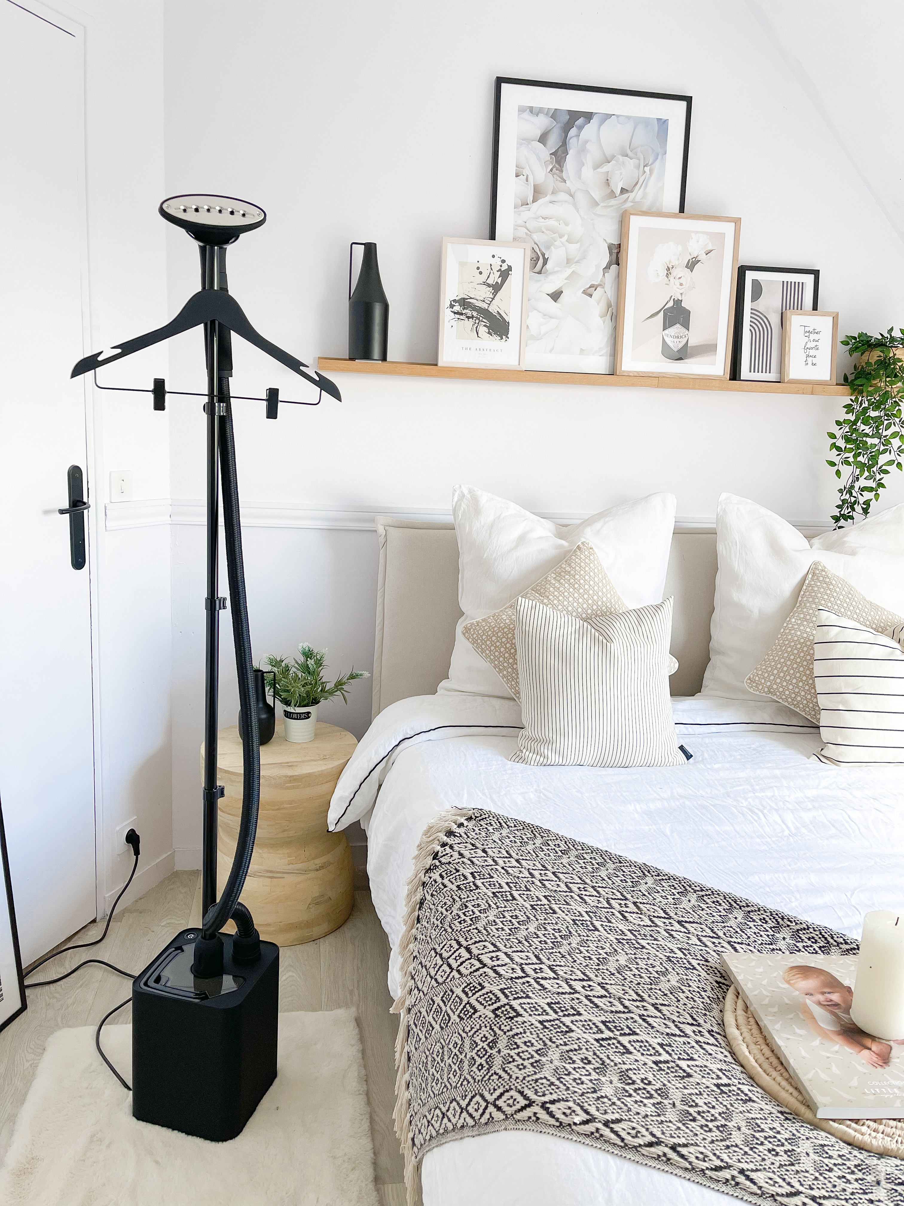 A bedroom scene with a steamer, bed, pictures, and decor.