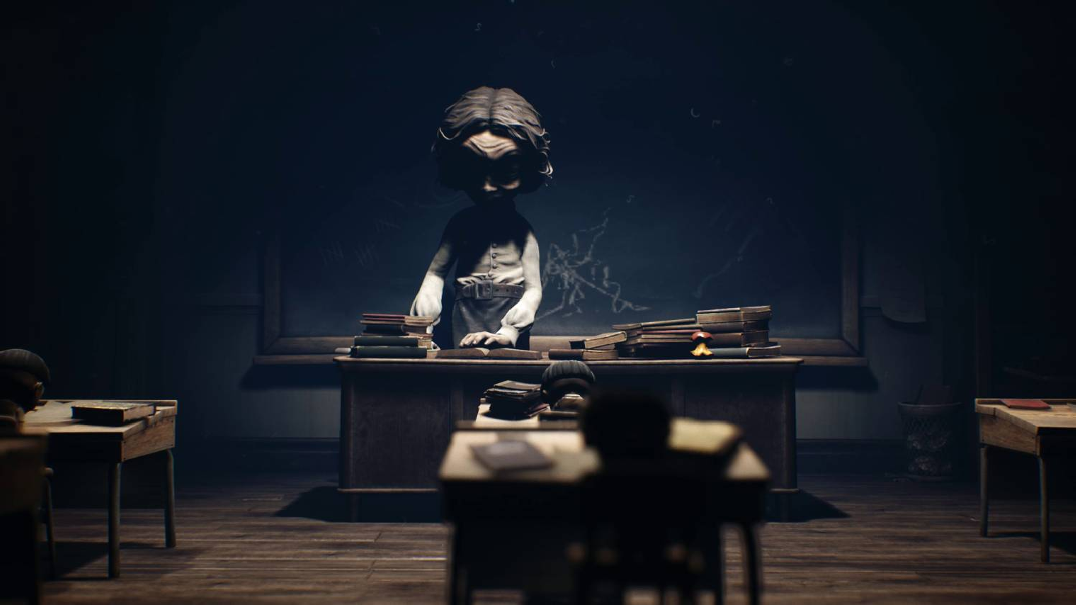Scena di classe buia, figura alla scrivania, libri, banchi.
