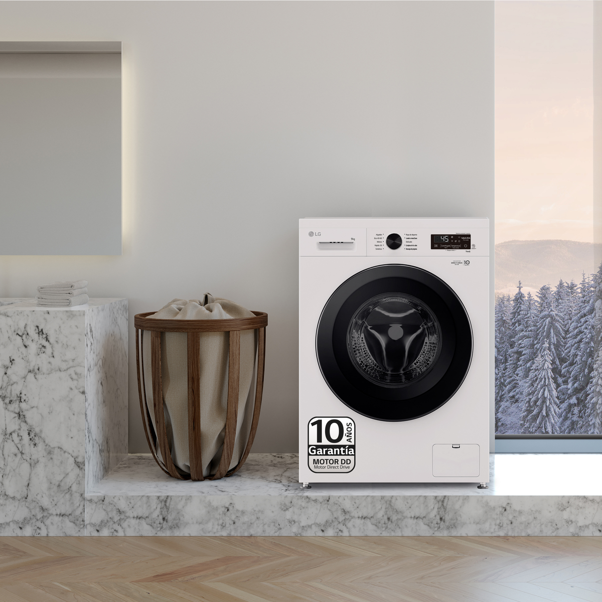 Biała pralka obok kosza na pranie i okna z zimowym widokiem.